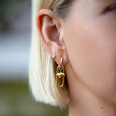 product_details::Daffodil Charm paired with Solid Link Huggie Hoop Earrings and styled with Huggie Gold Solid Snack Hoop Earrings on model.