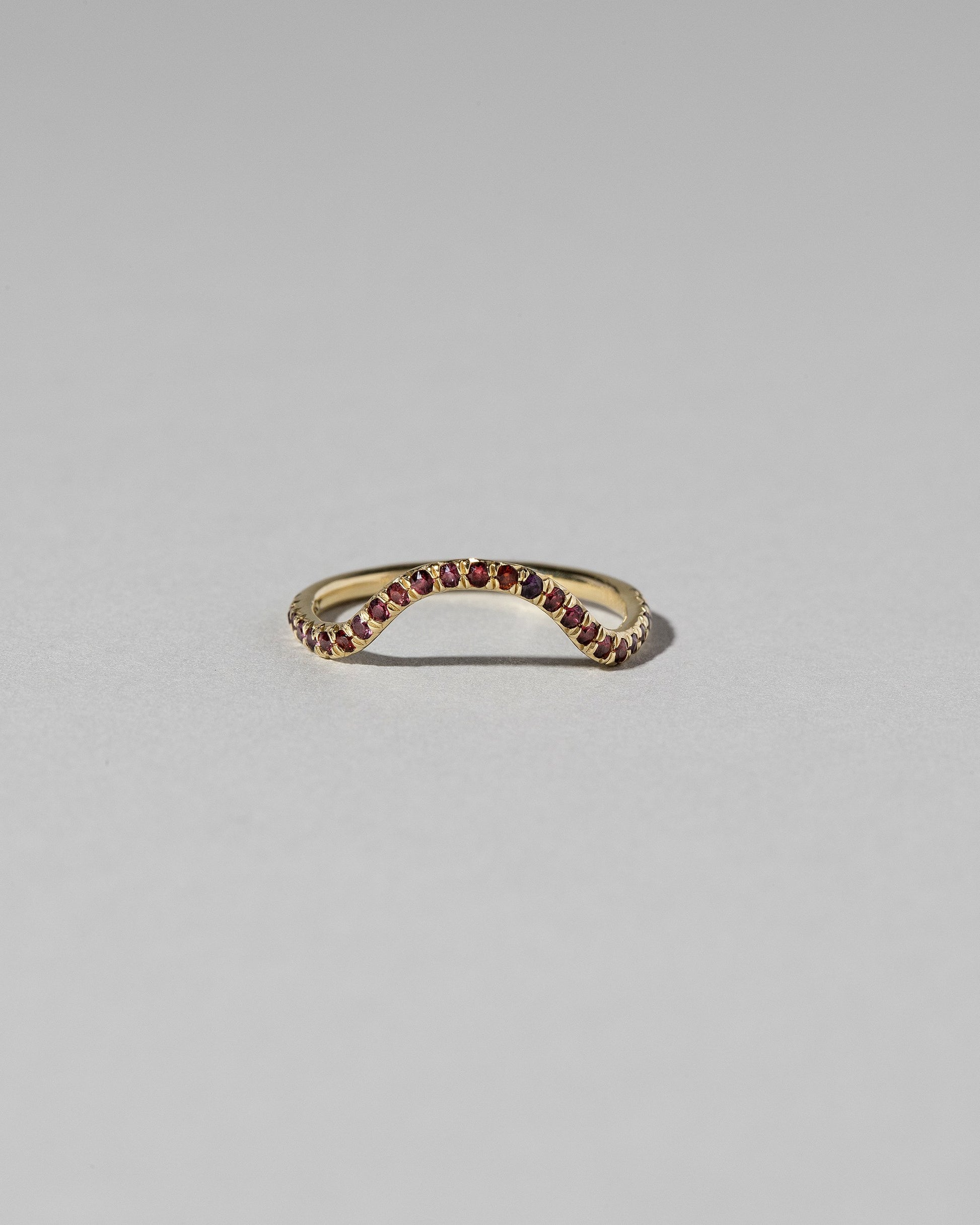 Gold Pavé Garnet Curve Band on light color background.