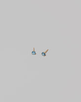 Petite Blue Topaz Martini Stud Earrings on light color background.