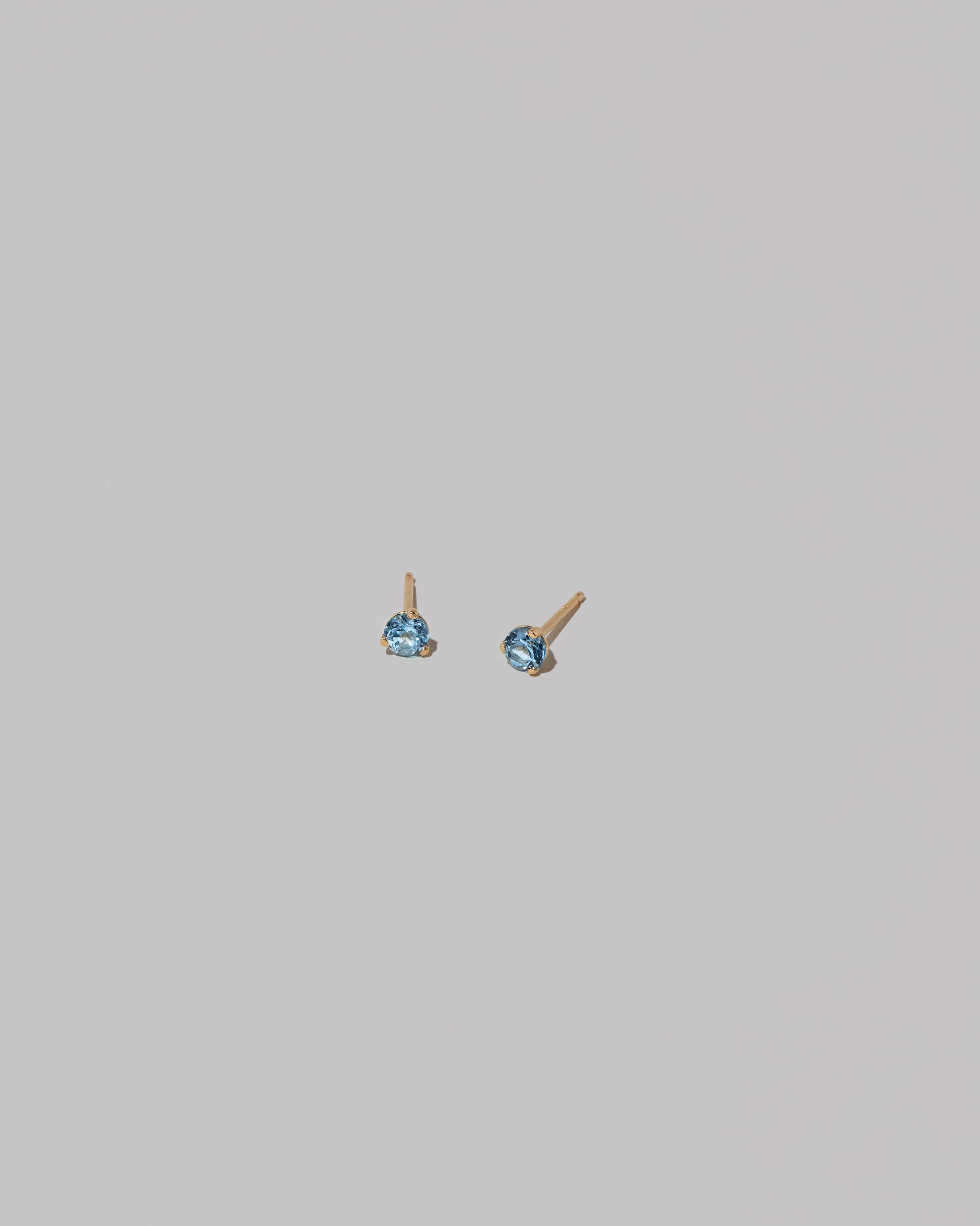Petite Blue Topaz Martini Stud Earrings on light color background.