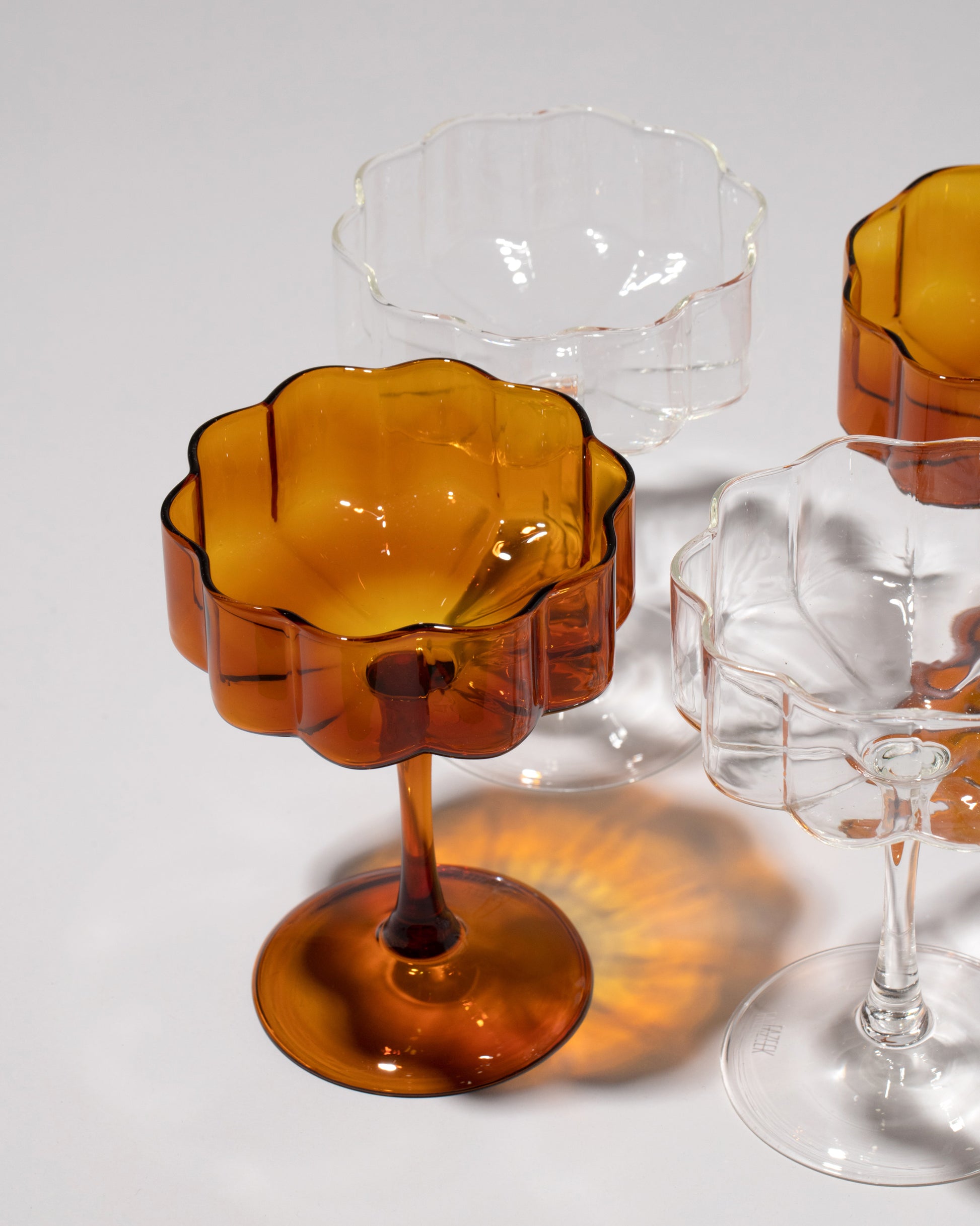 Closeup details of a group of Fazeek Clear and Amber Wave Coupe Sets on light color background.