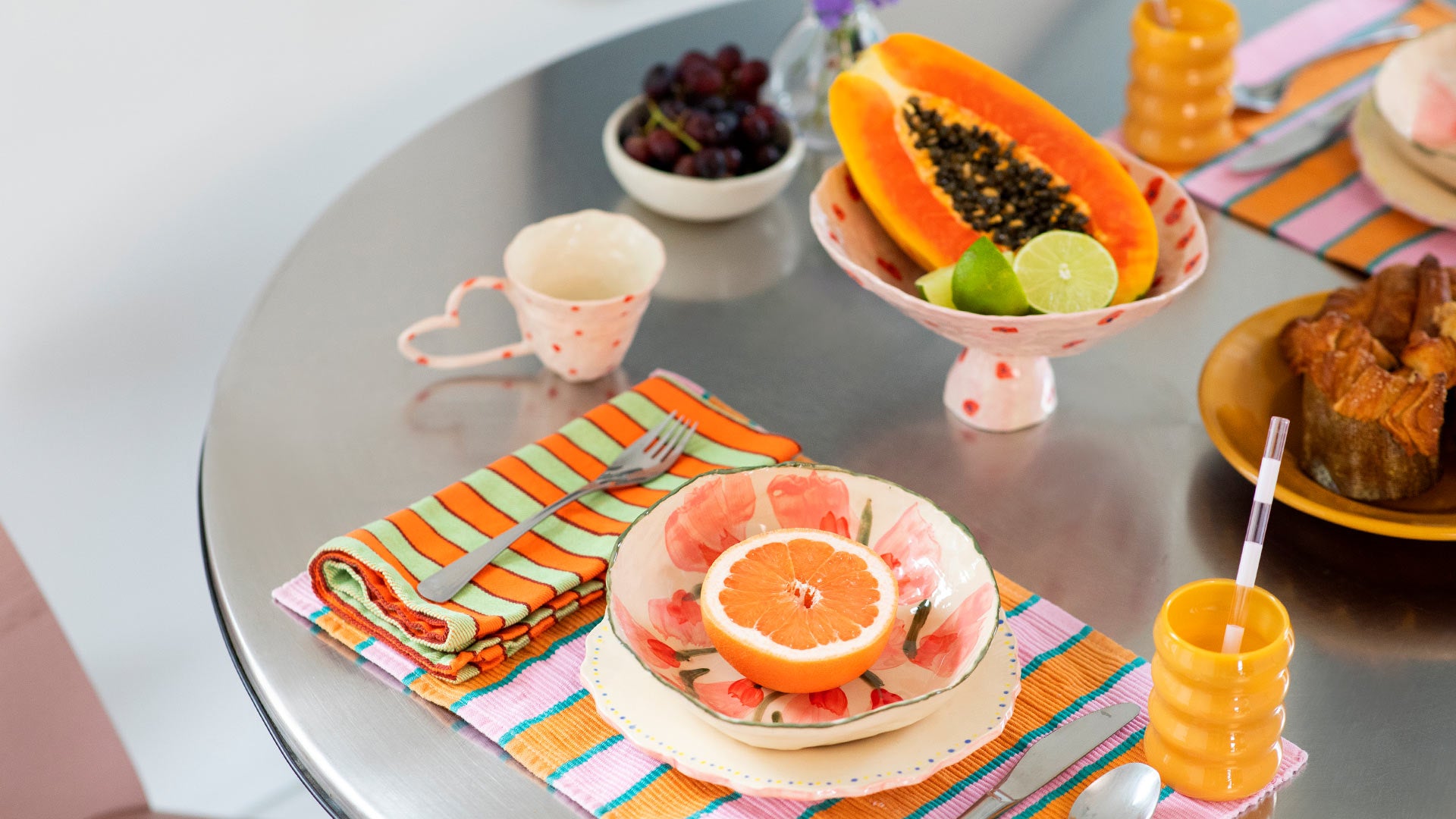 Editorial photo of dining table set with colorful plates and bowls by Samantha Kerdine and Opaque Ripple Cups by Sophie Lou Jacobson. 