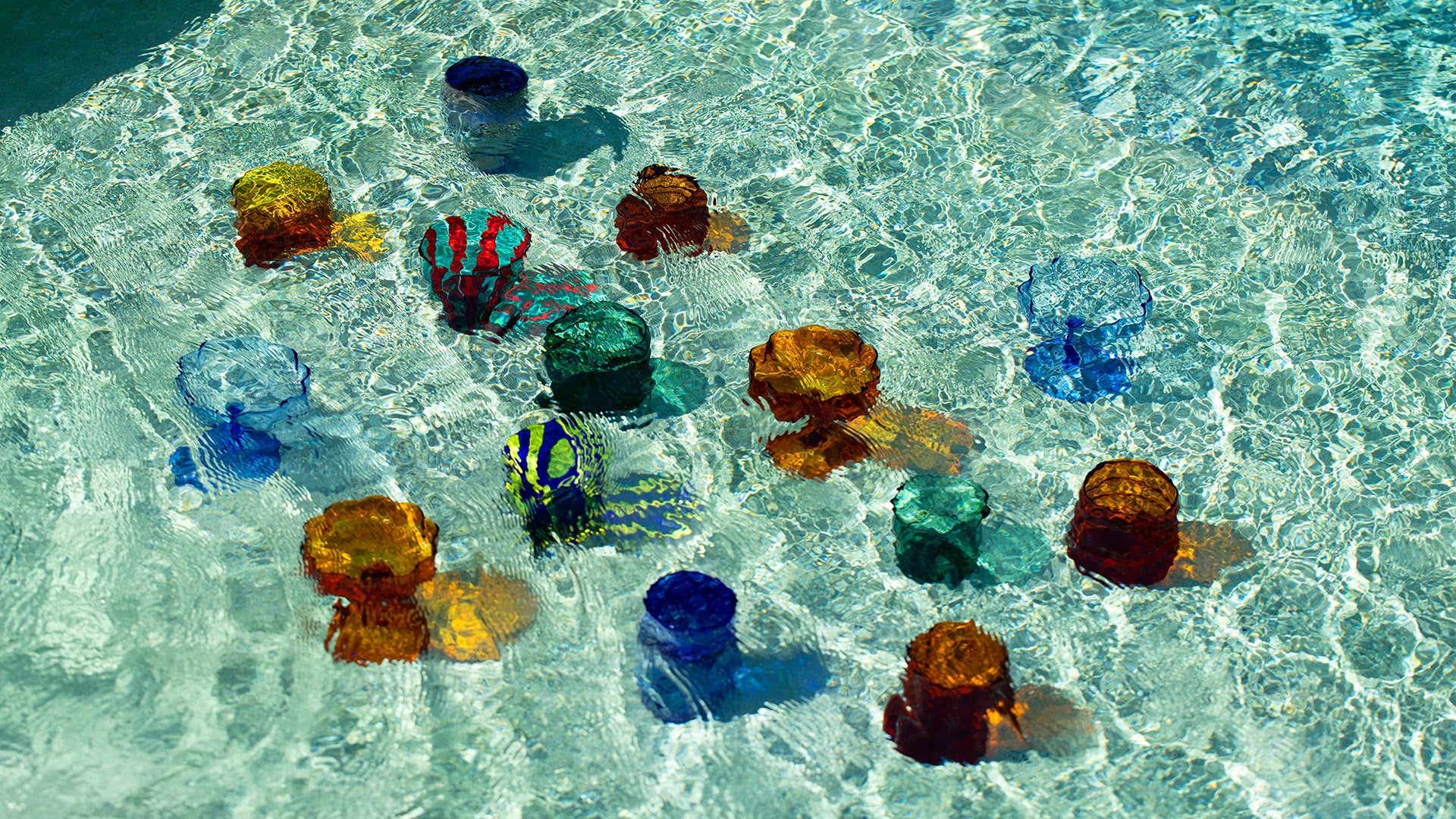 Editorial photo of a mix of colorful glassware under water in a pool