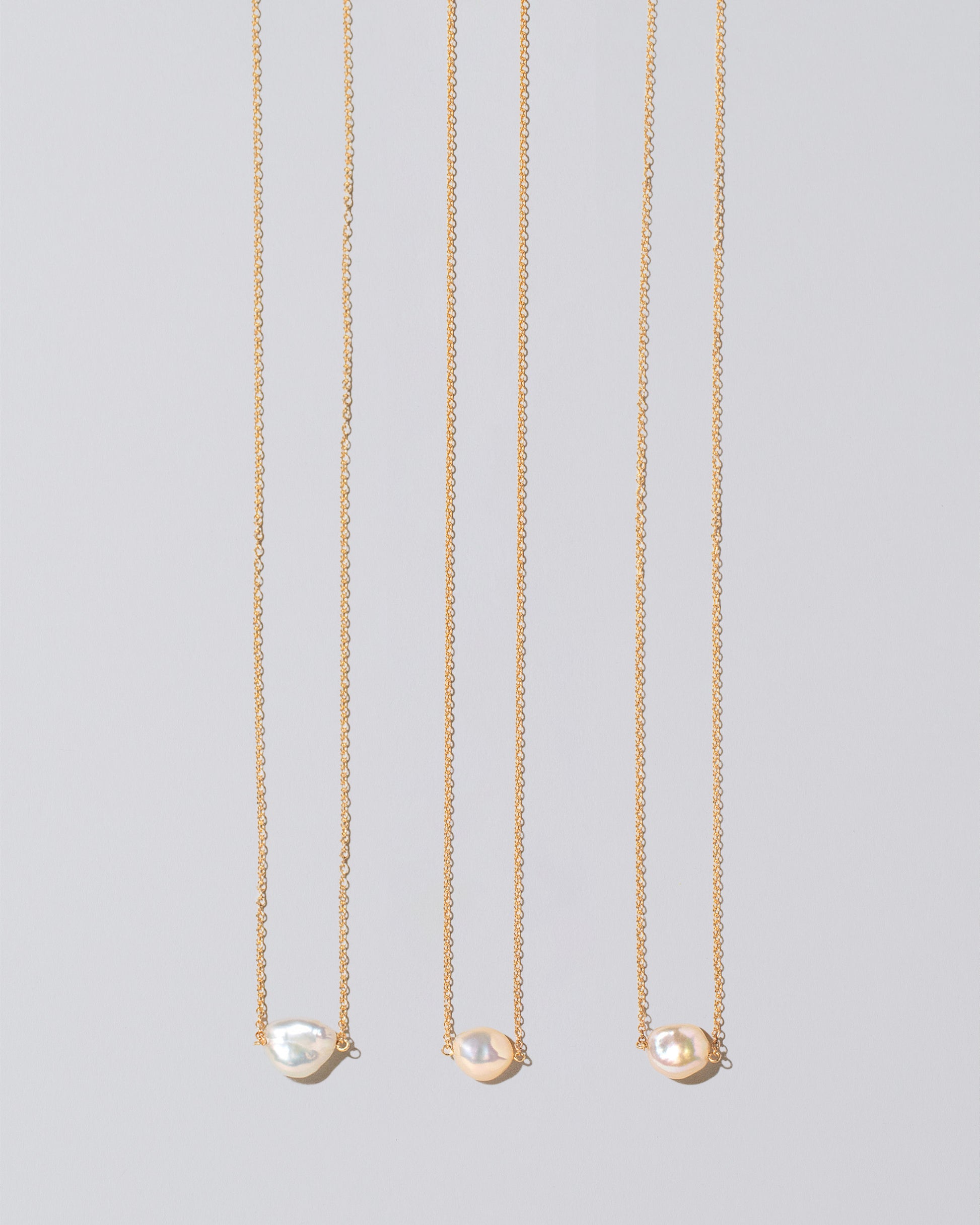 Group of the White Lagniappe Pearl Necklaces on light color background.