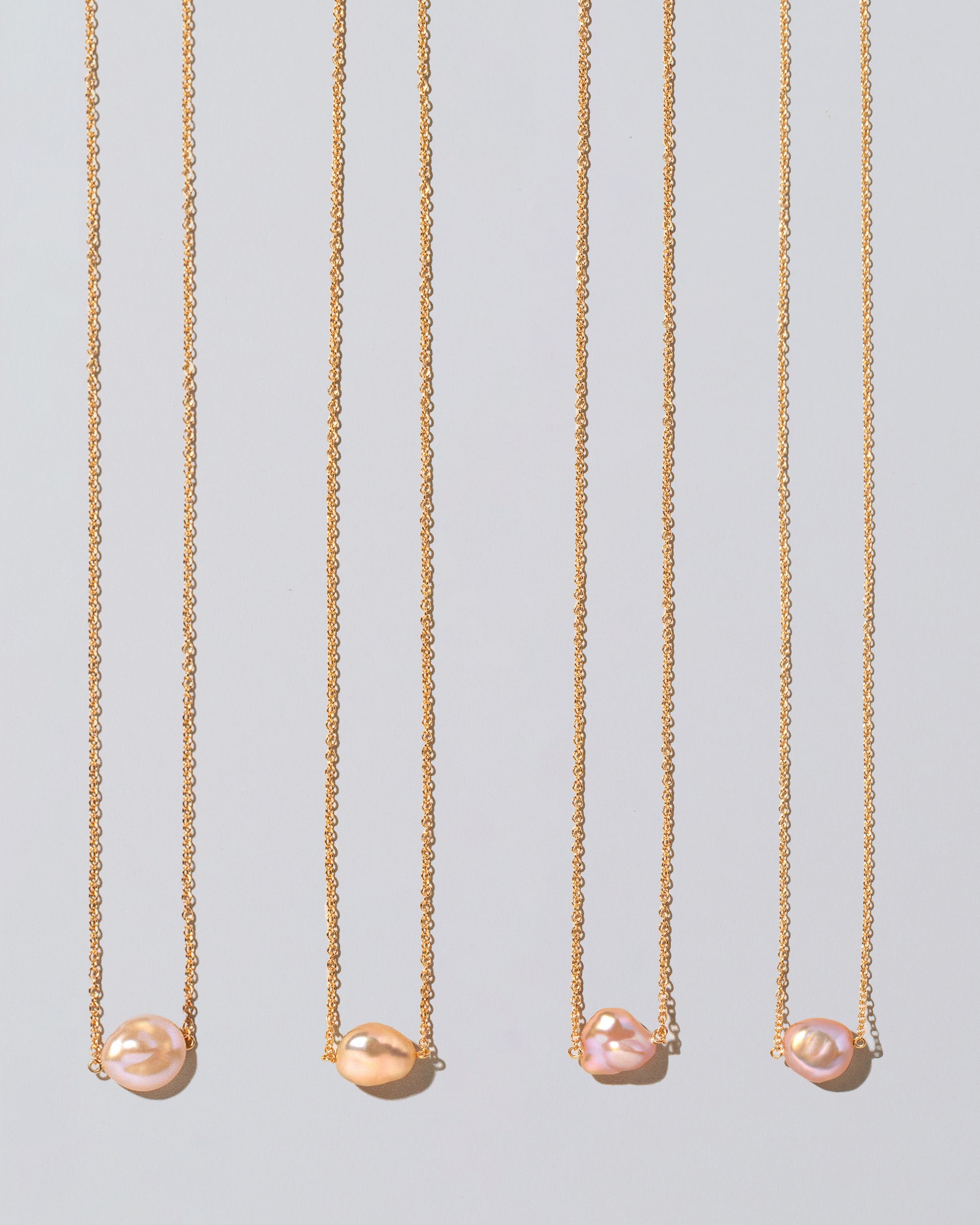 Group of Blush Pink Lagniappe Pearl Necklaces on light color background.