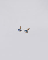 Blue Bicolor Sapphire Martini Stud Earrings on light color background.