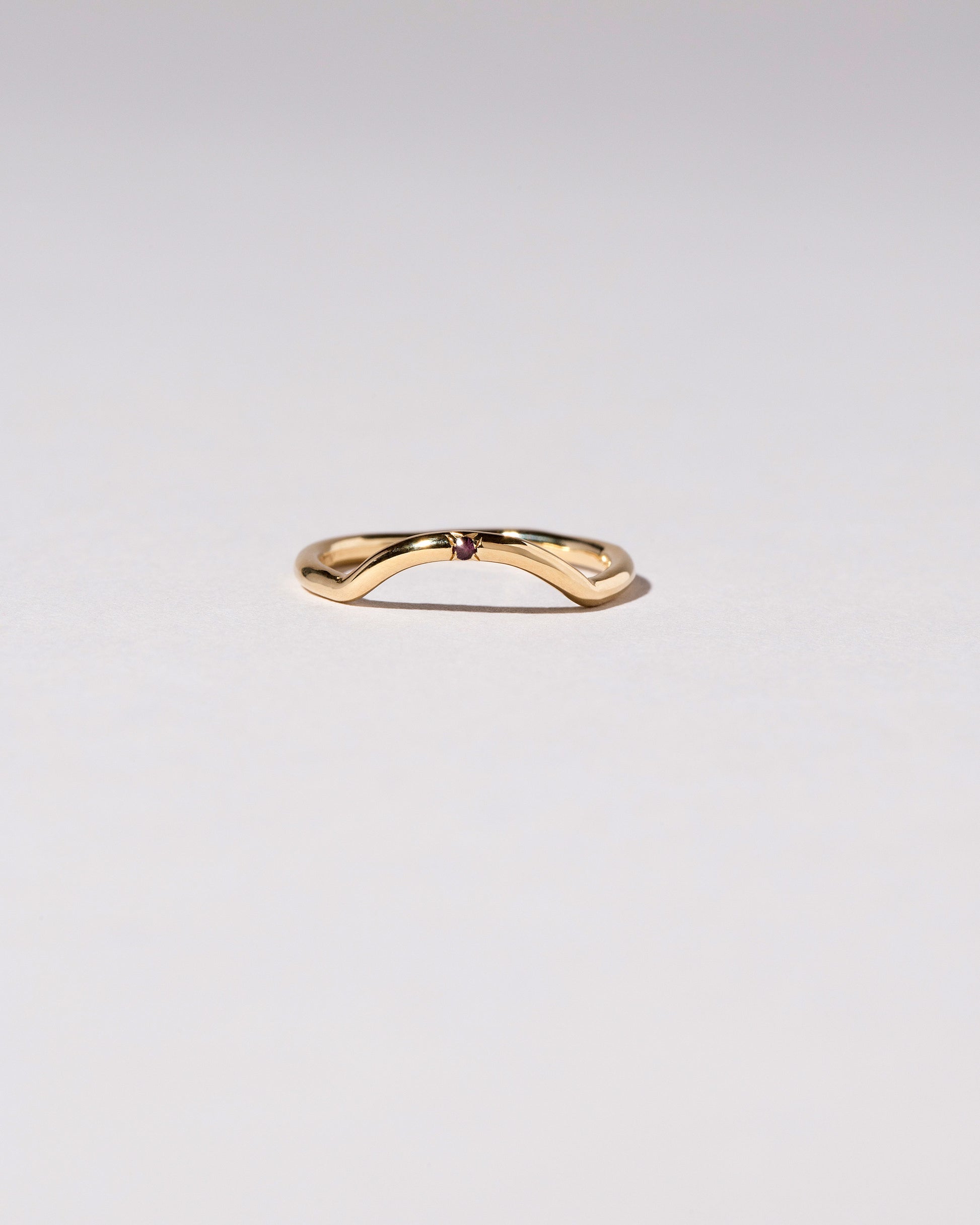 Gold Garnet Single Stone Mini Curve Band on light color background.