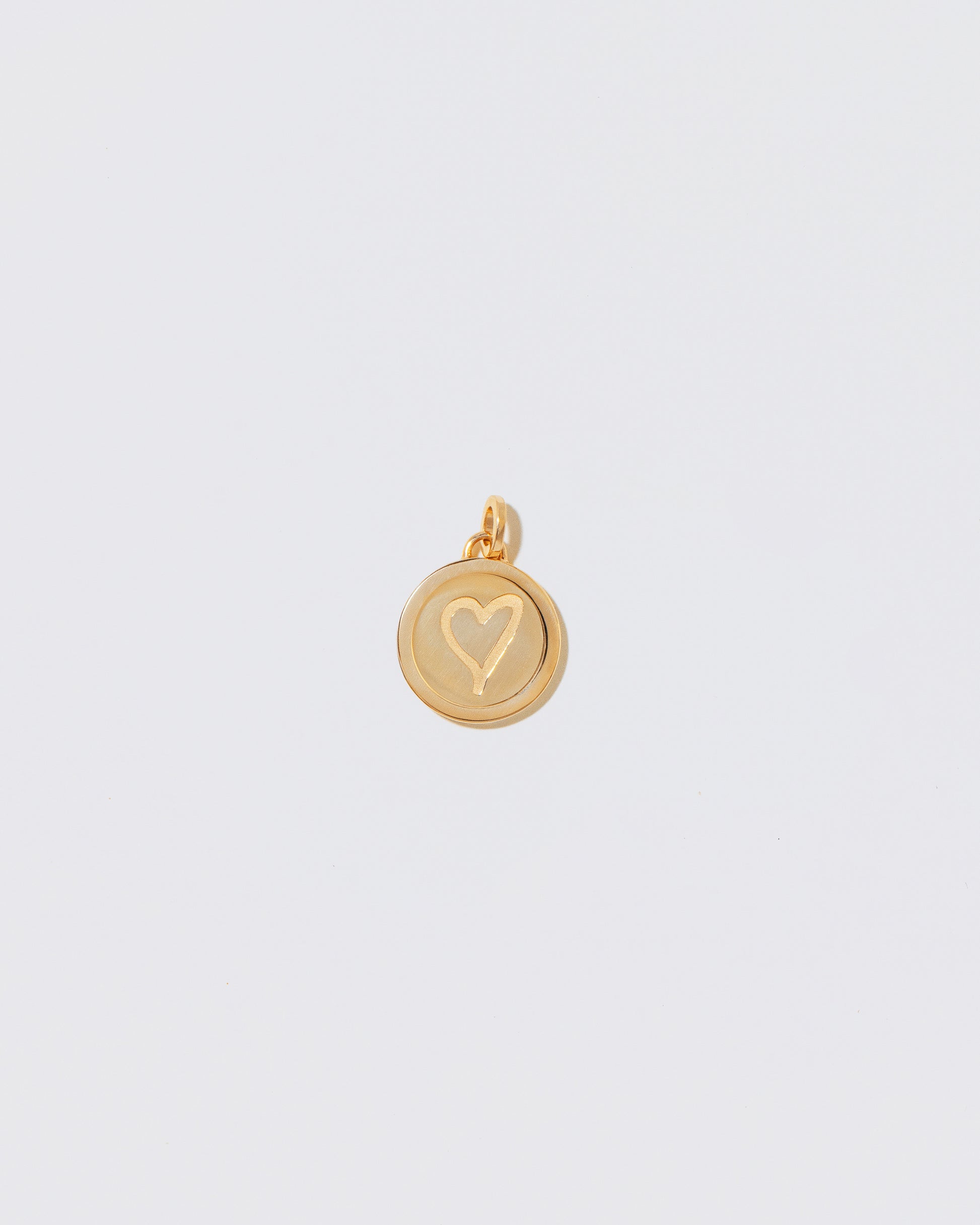 Finished Small Round Pendant Memento Pendant with engraved with a heart shape on light color background.