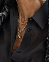 Styled image on model featuring the Petite Link Necklace with the Strawberry Charm, Bengal Curled-Up Cat Charm and Gold Large Thousand & One Night Heart Charm worn on its Oval Openable Link clasp, as well as the Accumulation Necklace and Tricolor Butter Chain Necklace.