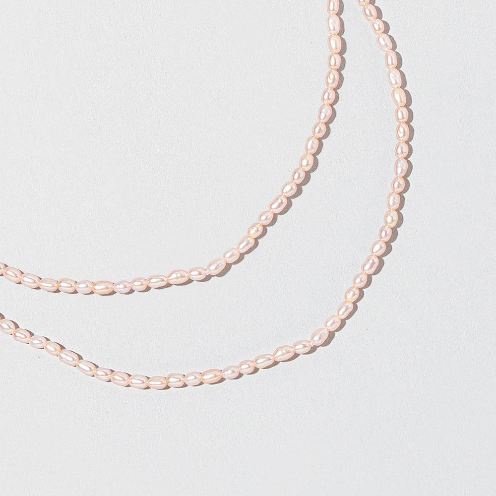 product_details::Closeup details of the Pink Peony Oval Pearl Necklaces on light color background.