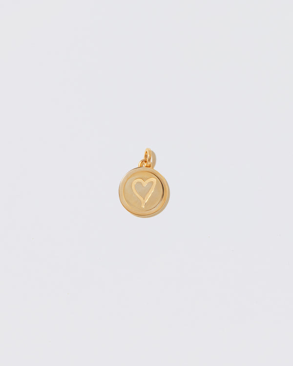 Finished Small Round Pendant Memento Pendant with engraved with a heart shape on light color background.