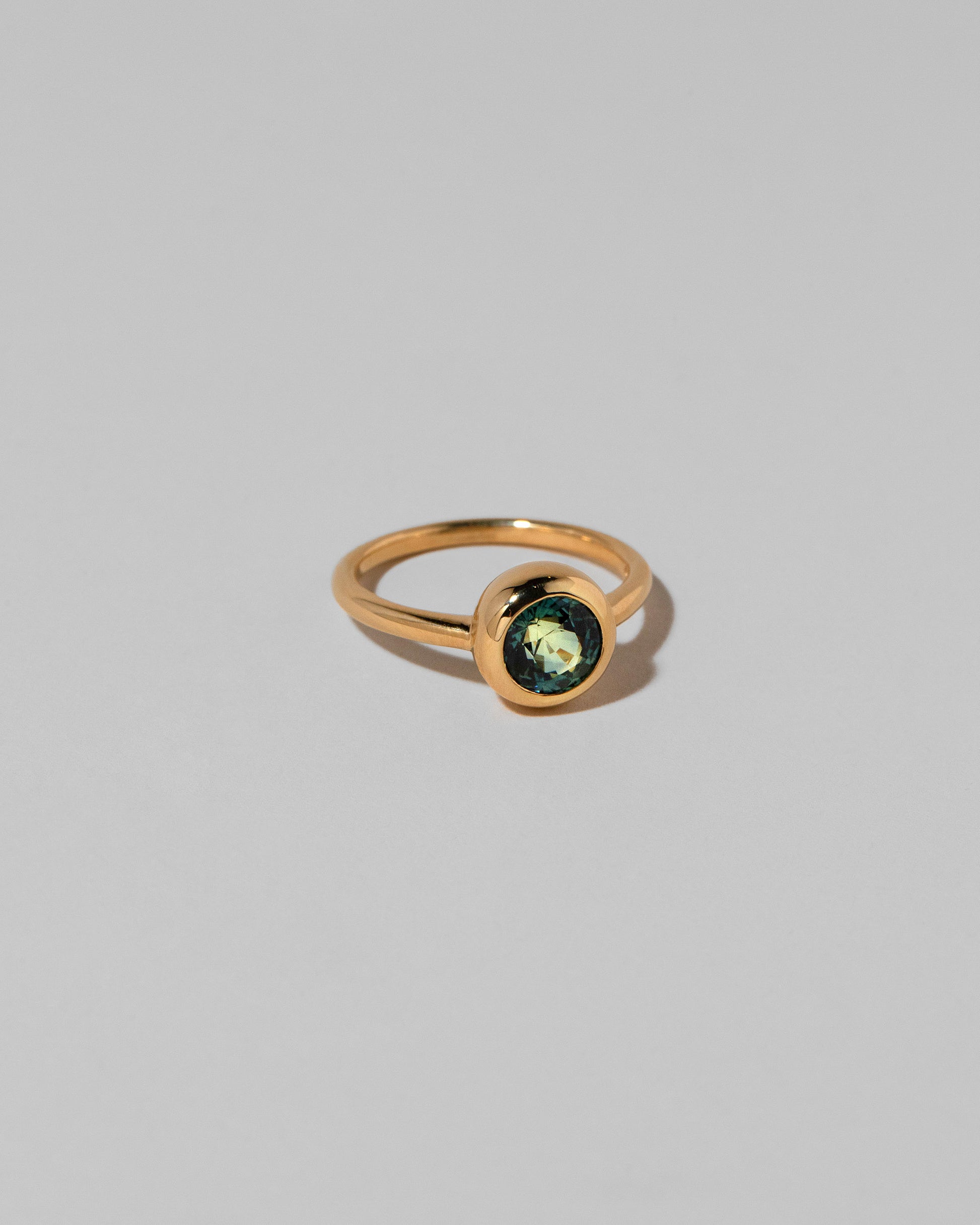 View from the side of the Teal Sapphire Wellspring Ring on light color background.