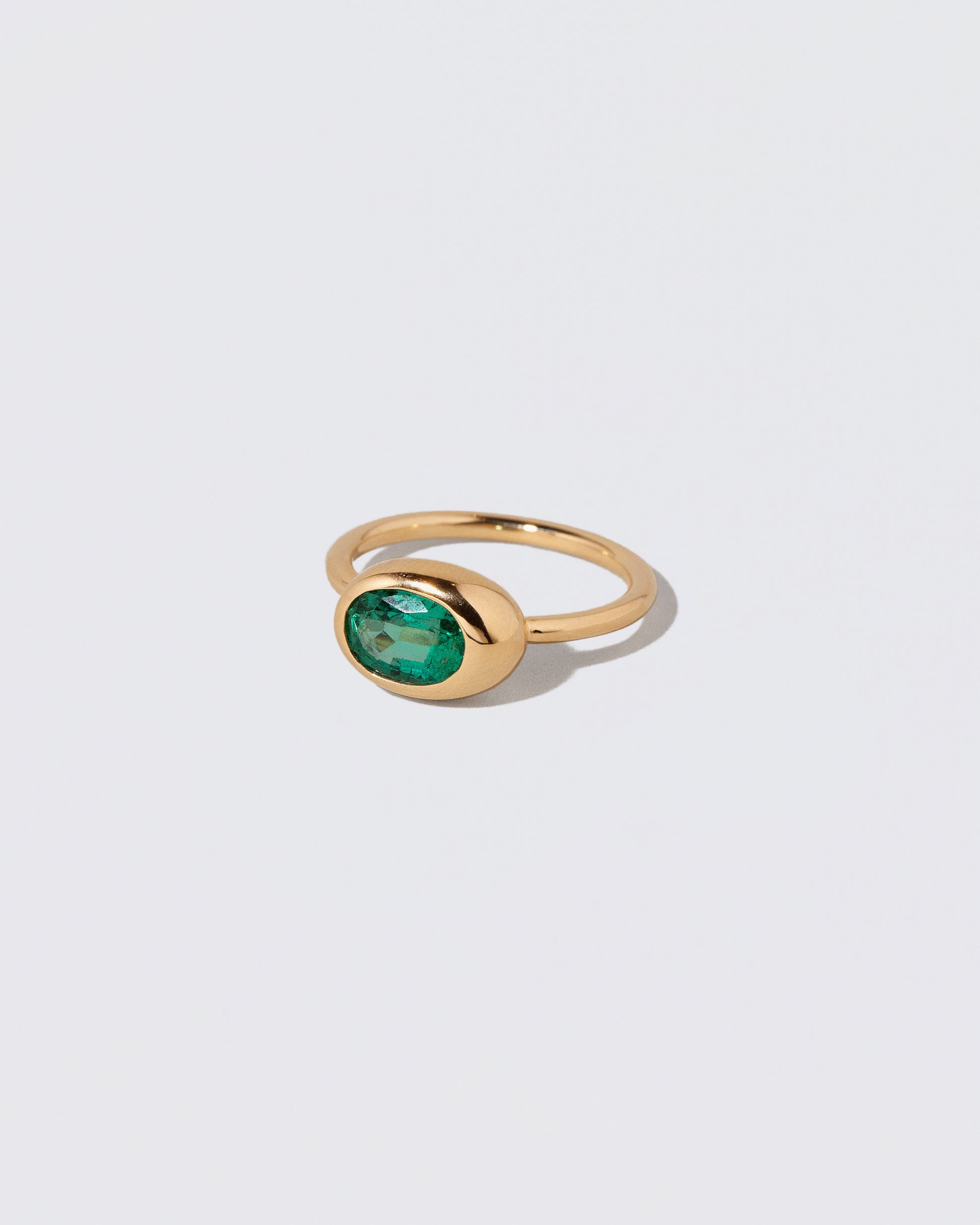 View from the side of the Oval Emerald Equalize Ring on light color background.