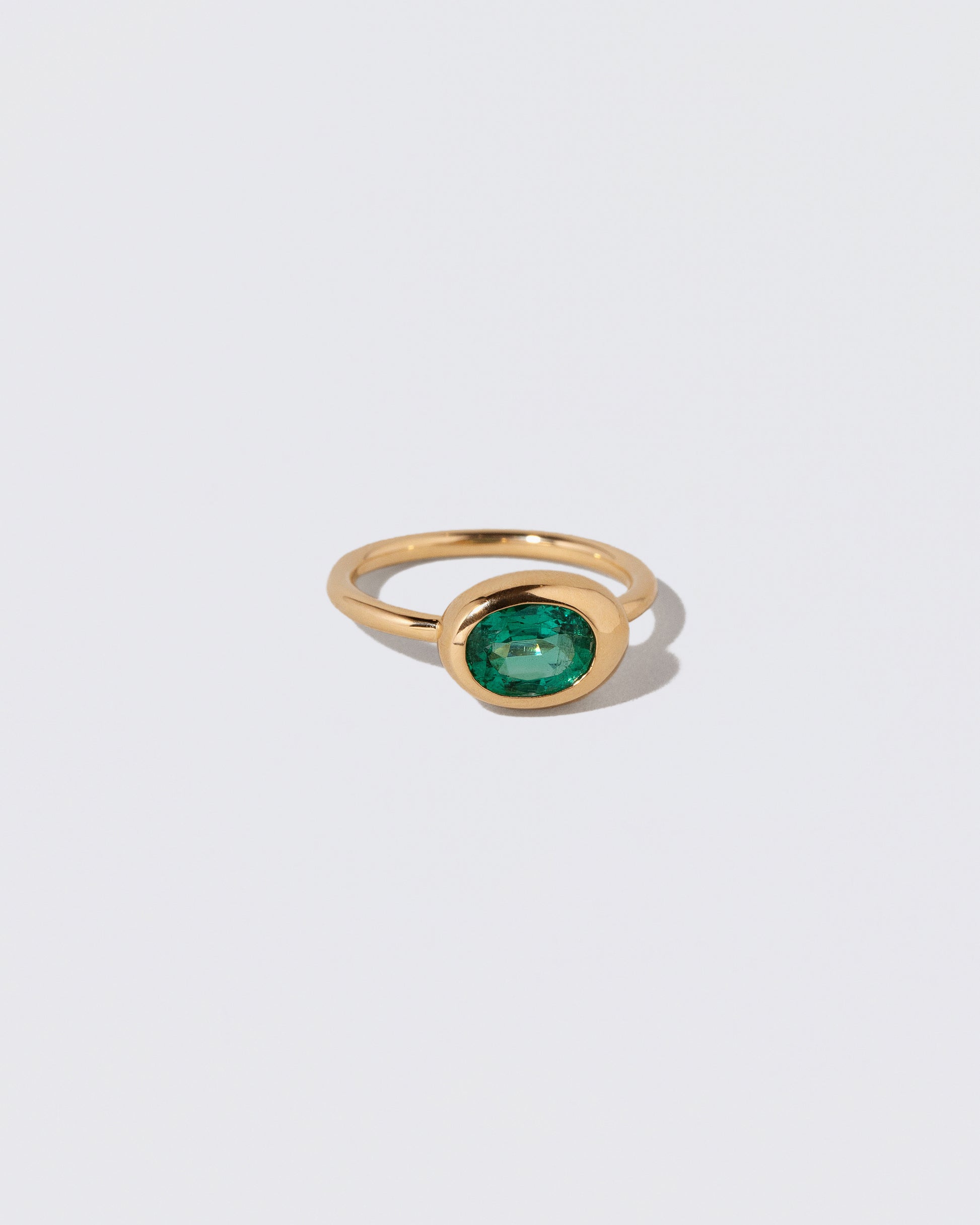 View from the side of the Oval Emerald Equalize Ring on light color background.