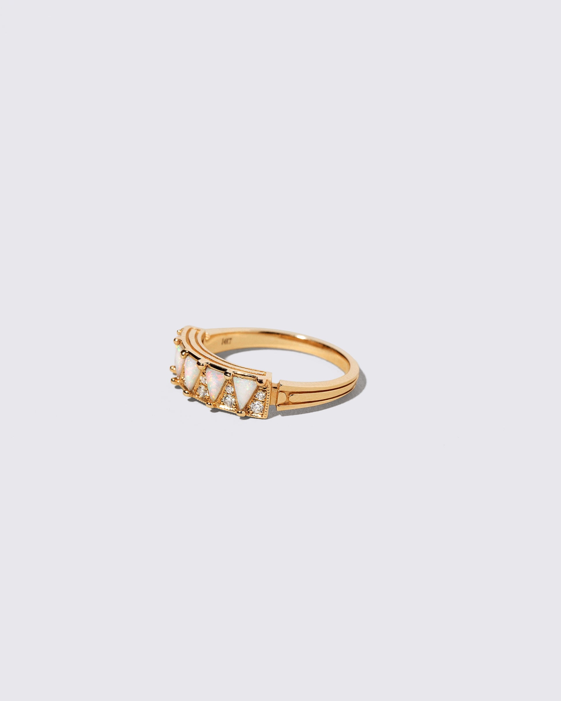 View from the side of the Gold White Opal Five Triangle Ring on light color background.