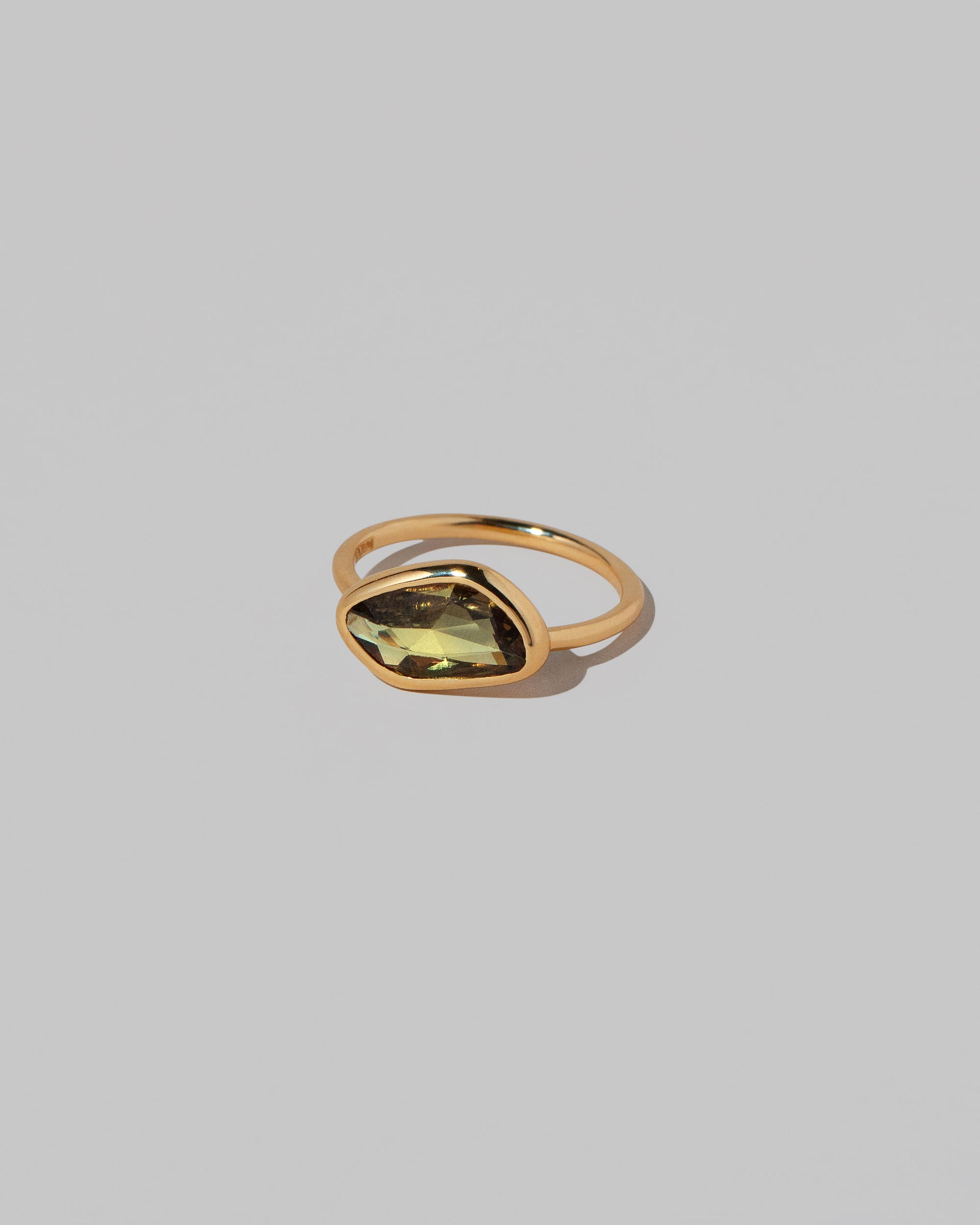 View from the side of the Gusher Green/Yellow Sapphire Ring 034 on light color background.