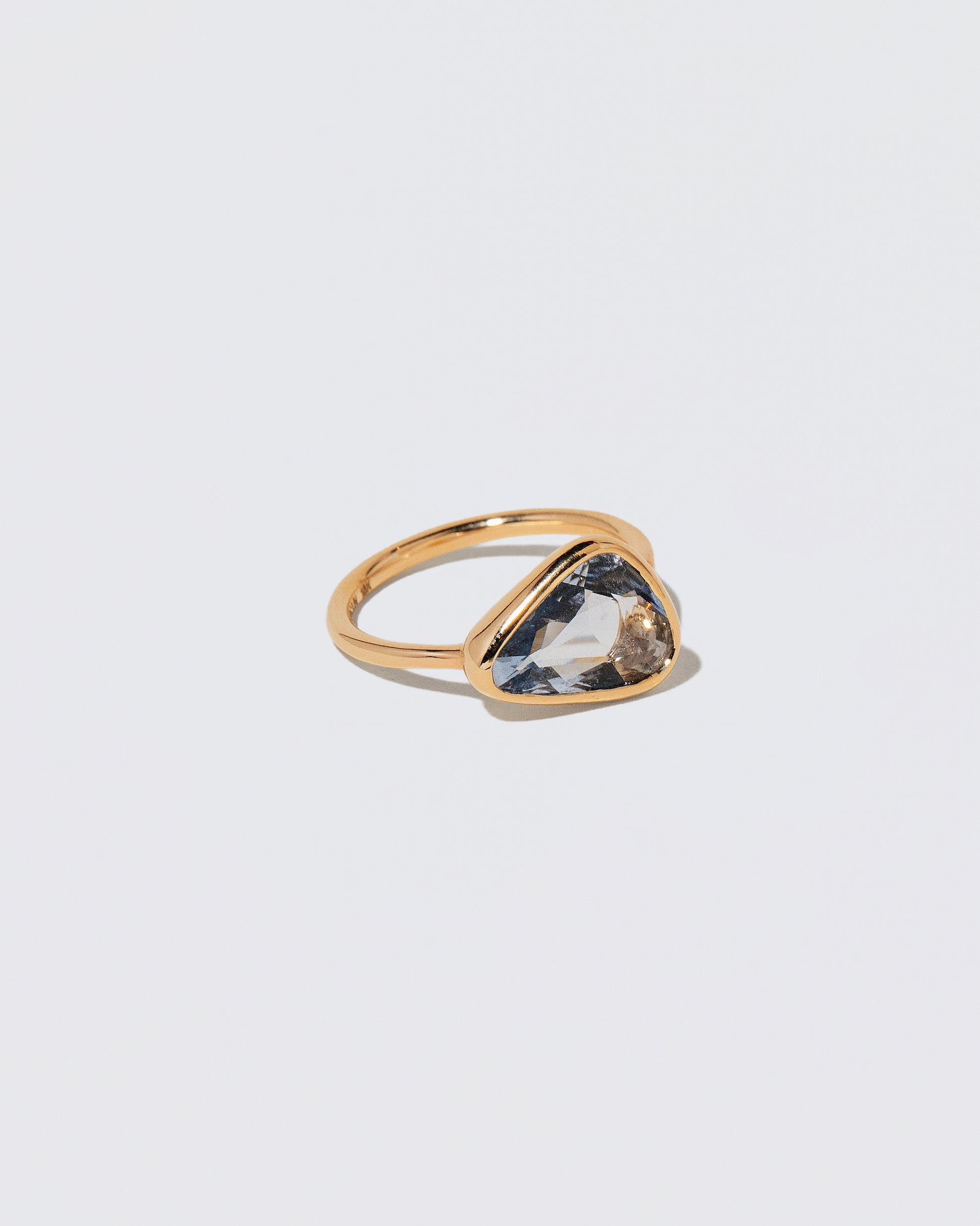 View from the side of the Gusher Blue Sapphire Ring 056 on light color background.