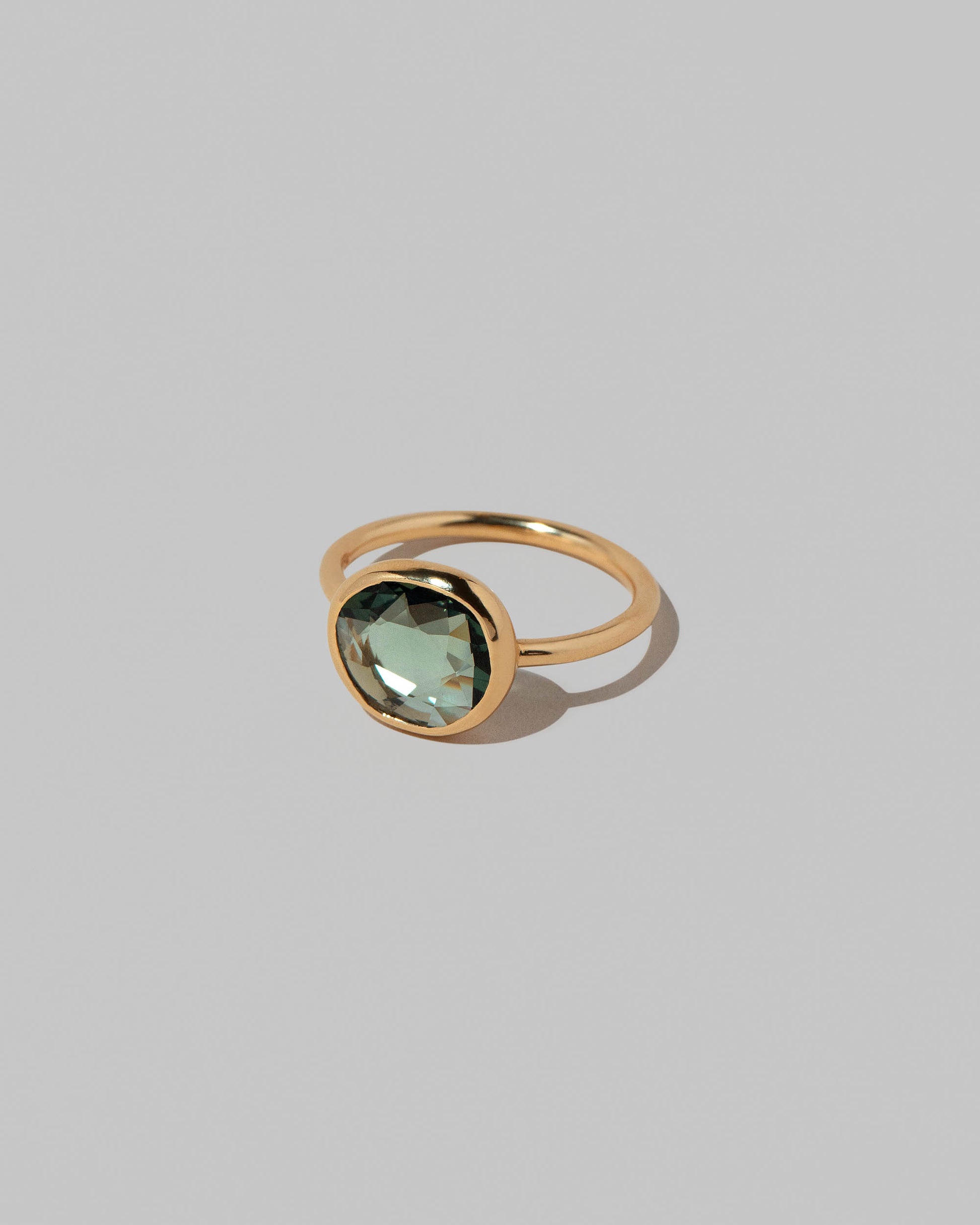 View from the side of the Gusher Green Sapphire Ring 032 on light color background.
