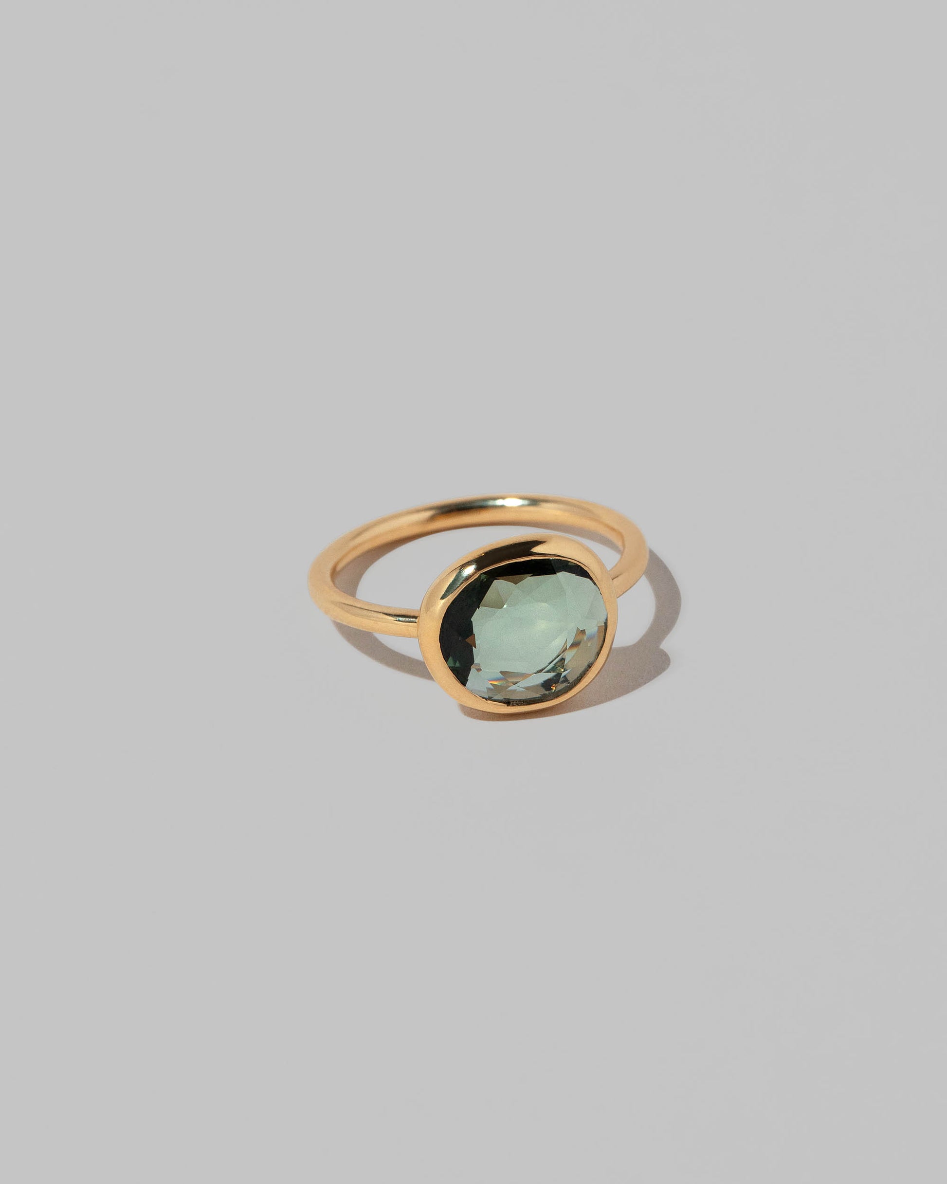 View from the side of the Gusher Green Sapphire Ring 032 on light color background.