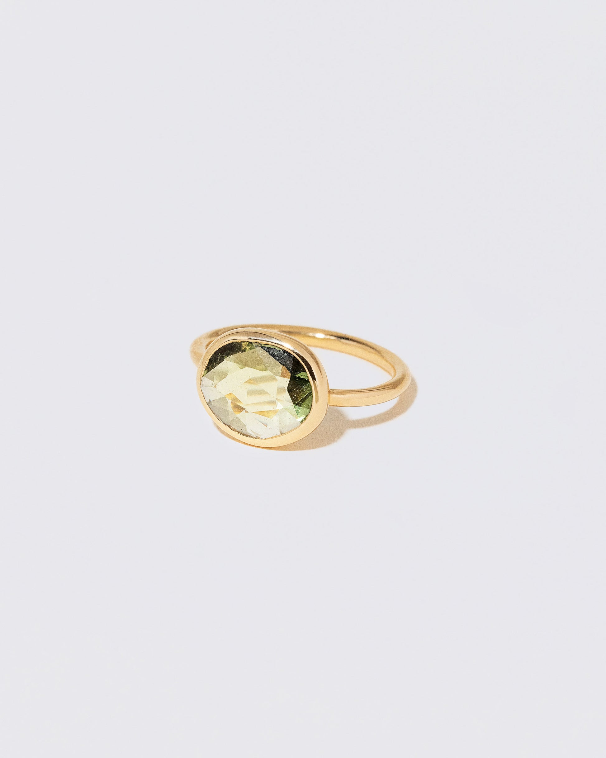 View from the side of the Gusher Green Sapphire Ring 052 on light color background.