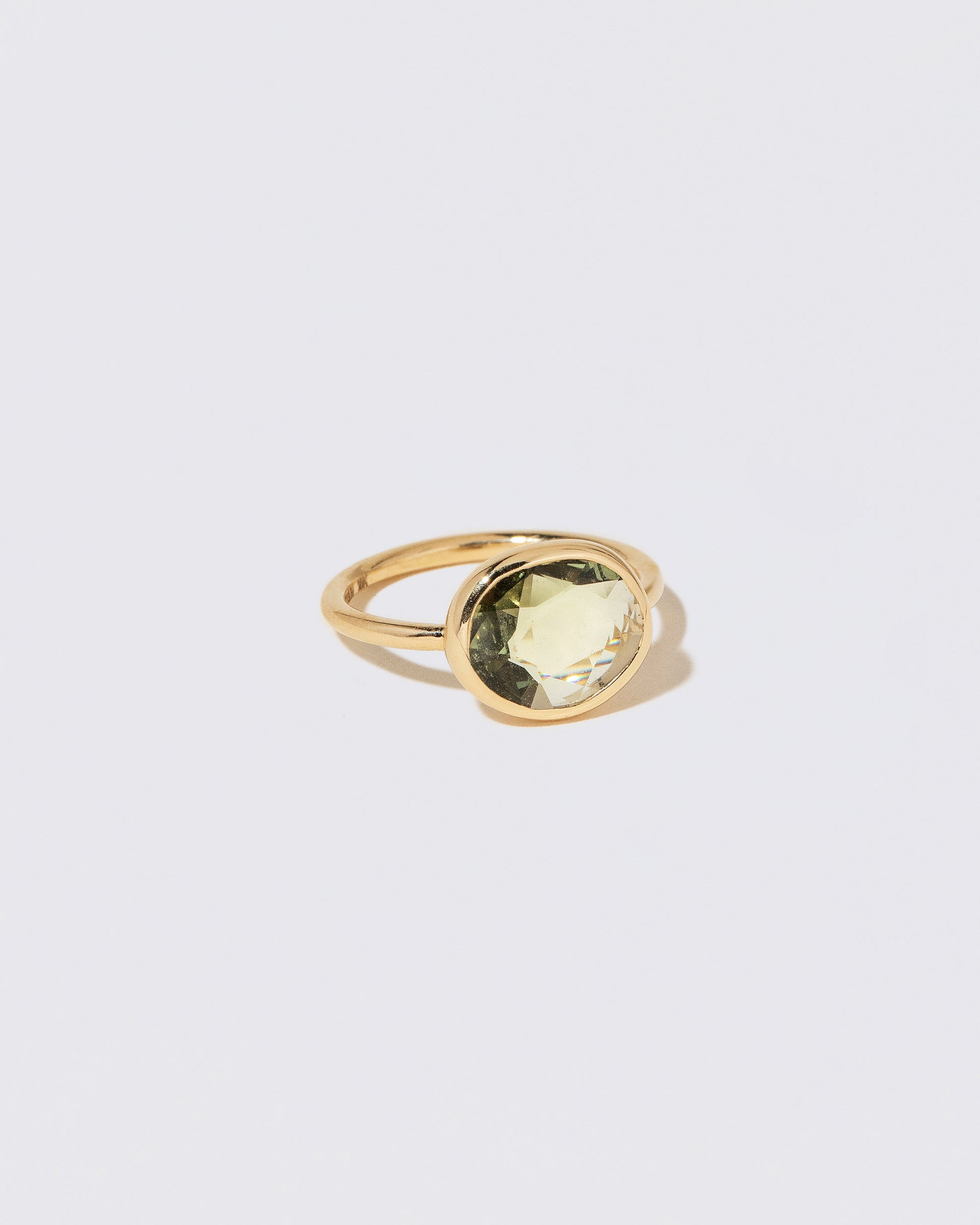 View from the side of the Gusher Green Sapphire Ring 052 on light color background.