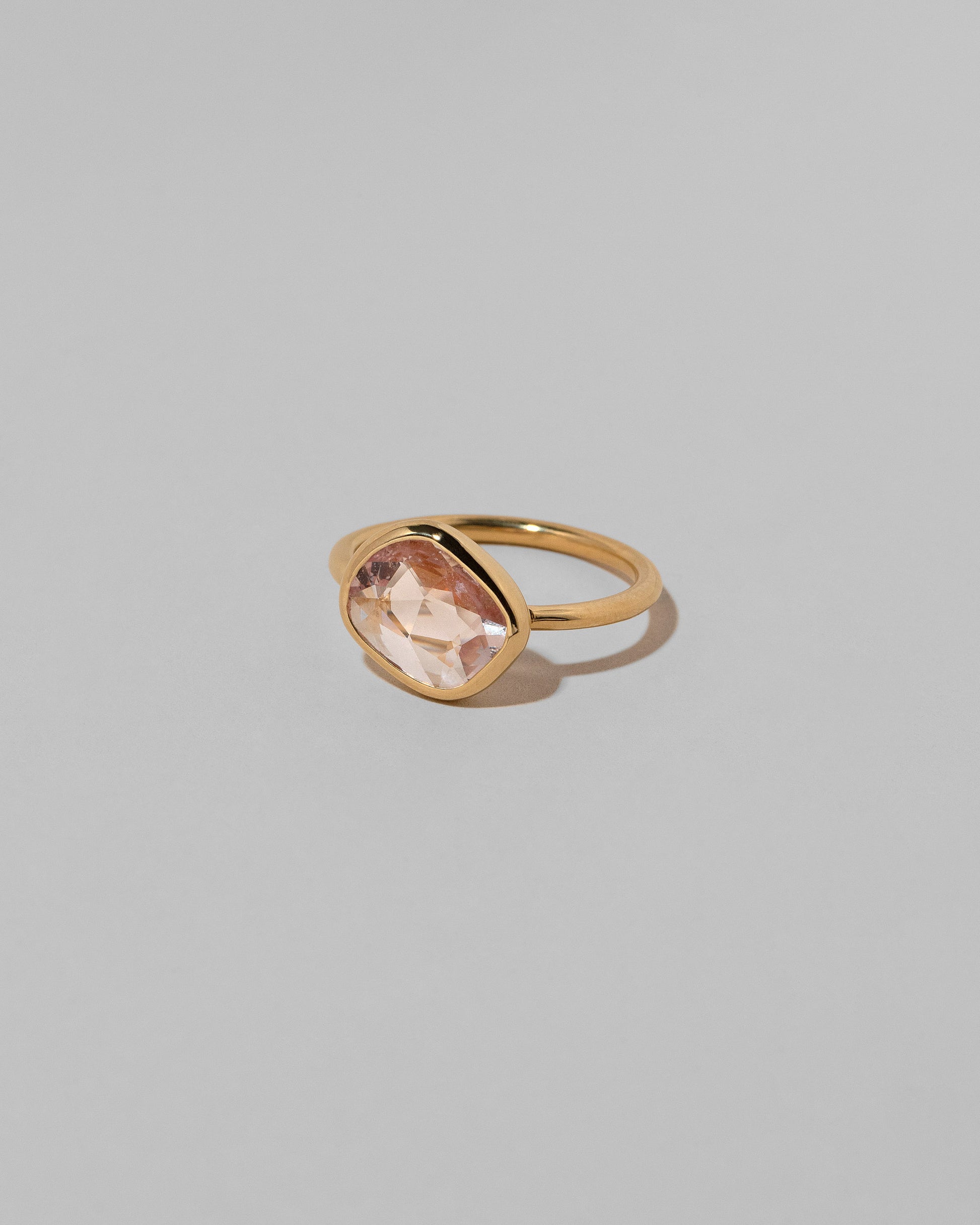 View from the side of the Gusher Pink Sapphire Ring 040 on light color background.