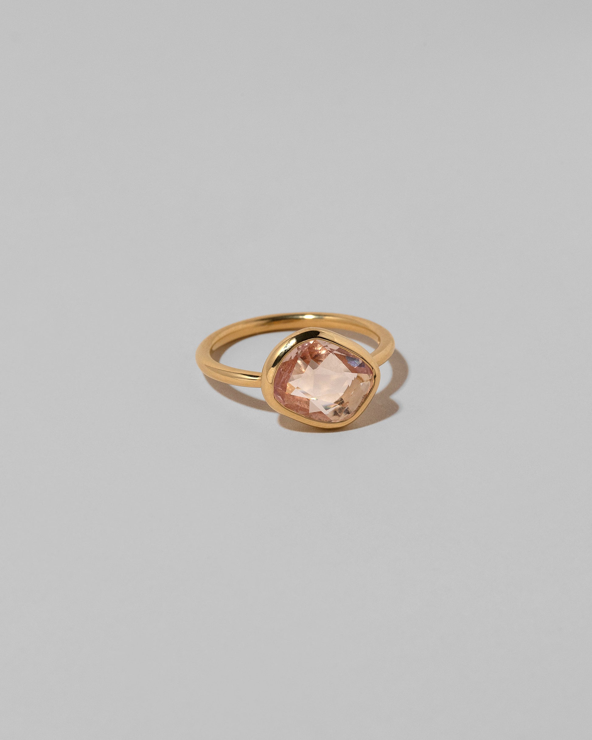 View from the side of the Gusher Pink Sapphire Ring 040 on light color background.