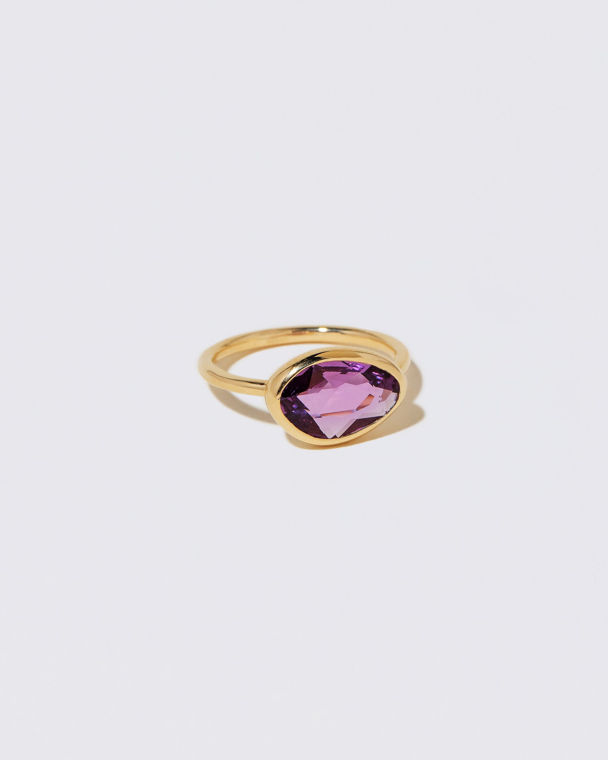 View from the side of the Gusher Pink Sapphire Ring 053 on light color background.