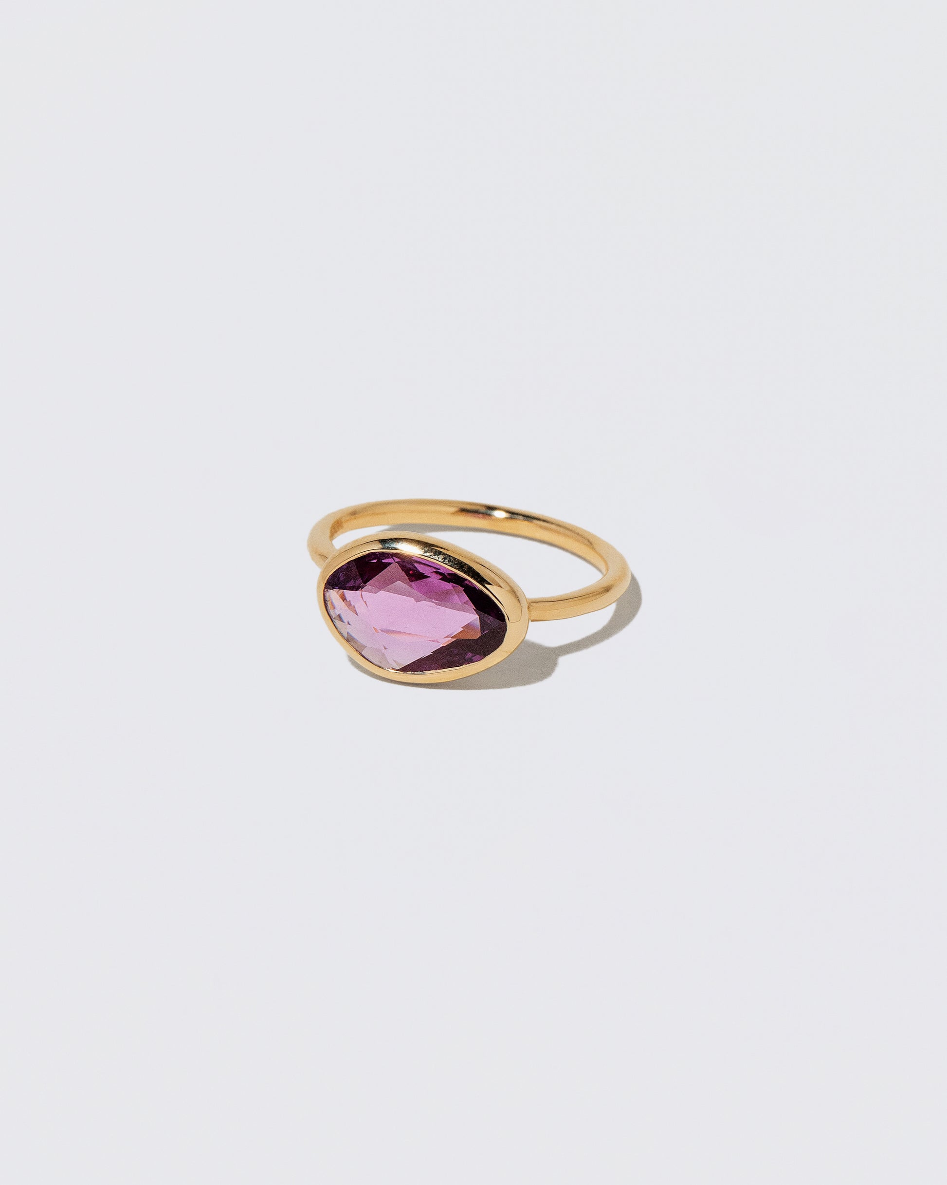 View from the side of the Gusher Pink Sapphire Ring 053 on light color background.