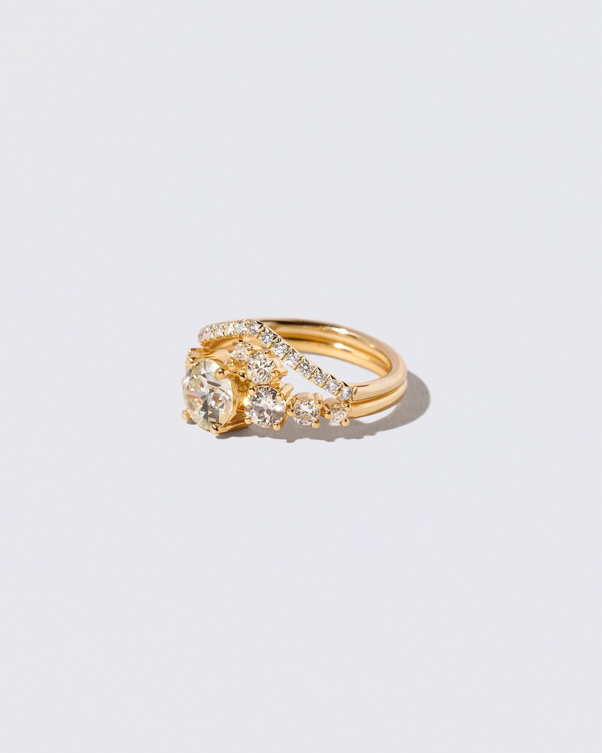 View from the side of the White Diamond Luna Ring and Gold White Diamond Pavé Luna Peak Band on light color background.