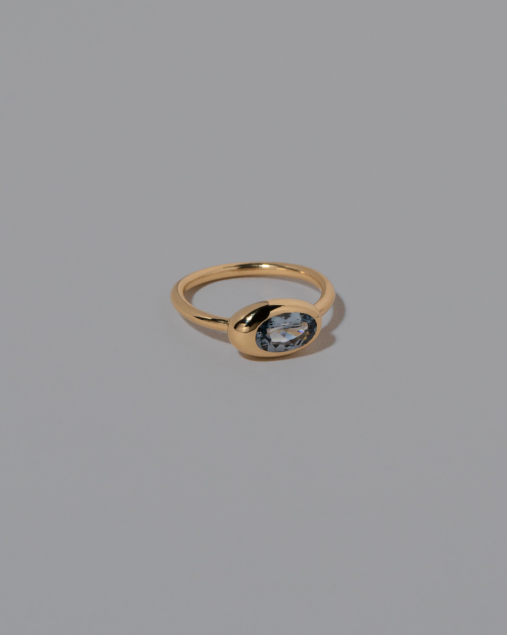 View from the side of the Oval Blue Sapphire Equalize Ring on light color background.