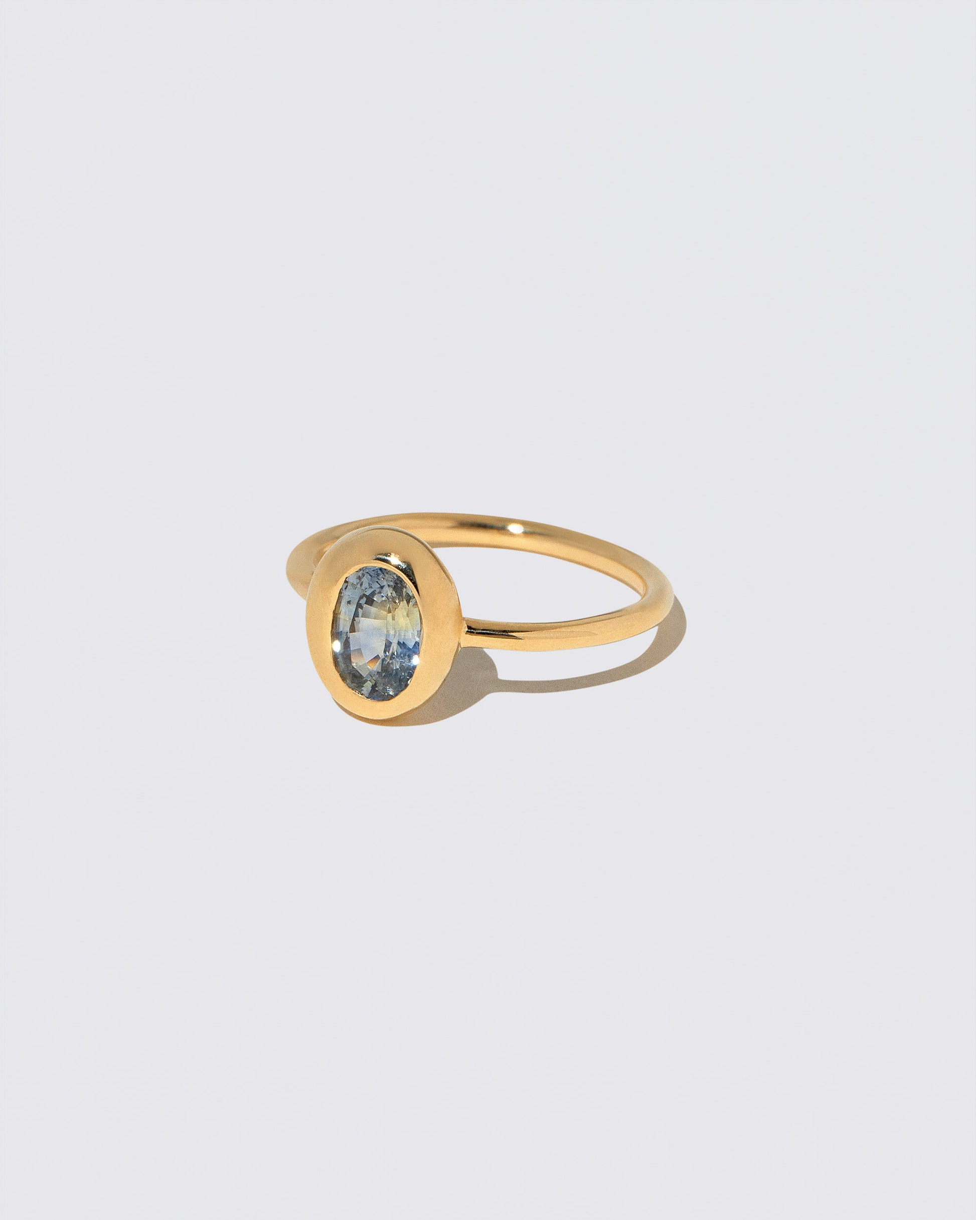 View from the side of the Oval Bicolor Sapphire Precise Ring on light color background.