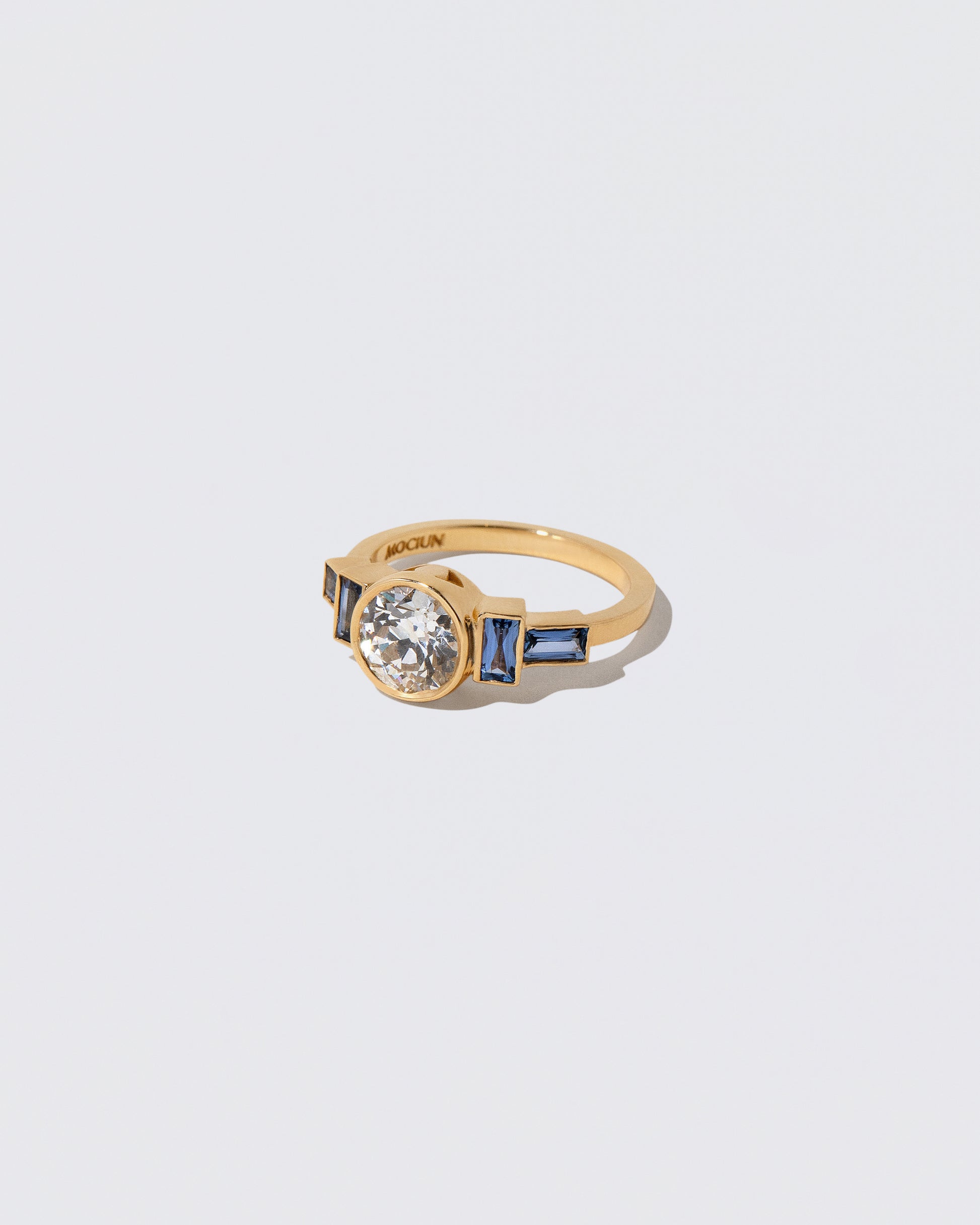 View from the side of the White Diamond & Blue Sapphire Third Eye Ring on light color background.