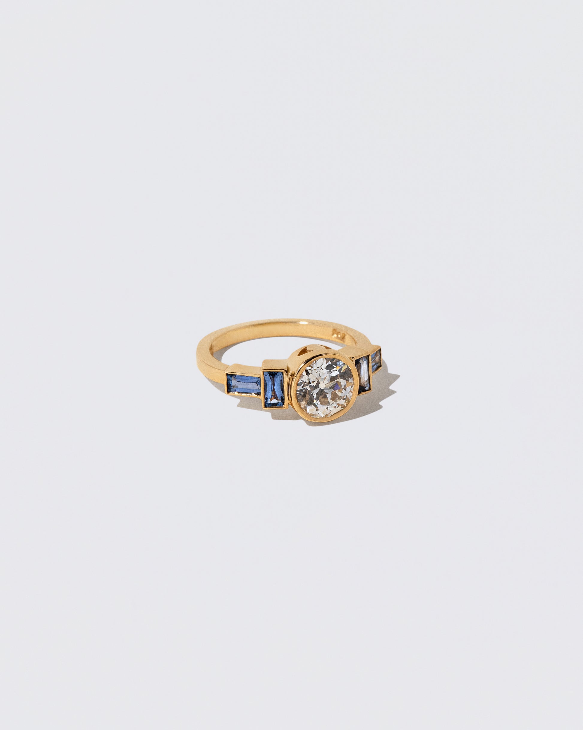 View from the side of the White Diamond & Blue Sapphire Third Eye Ring on light color background.
