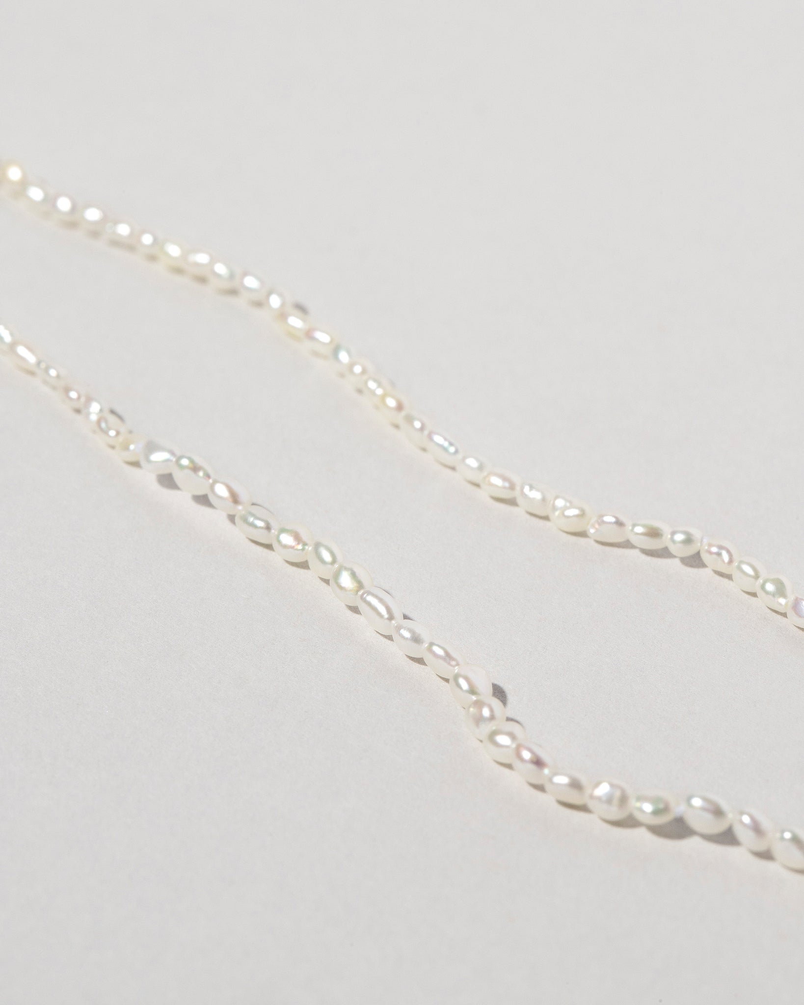Closeup details of the White Oval Seed Pearl Choker Necklaces on light color background.