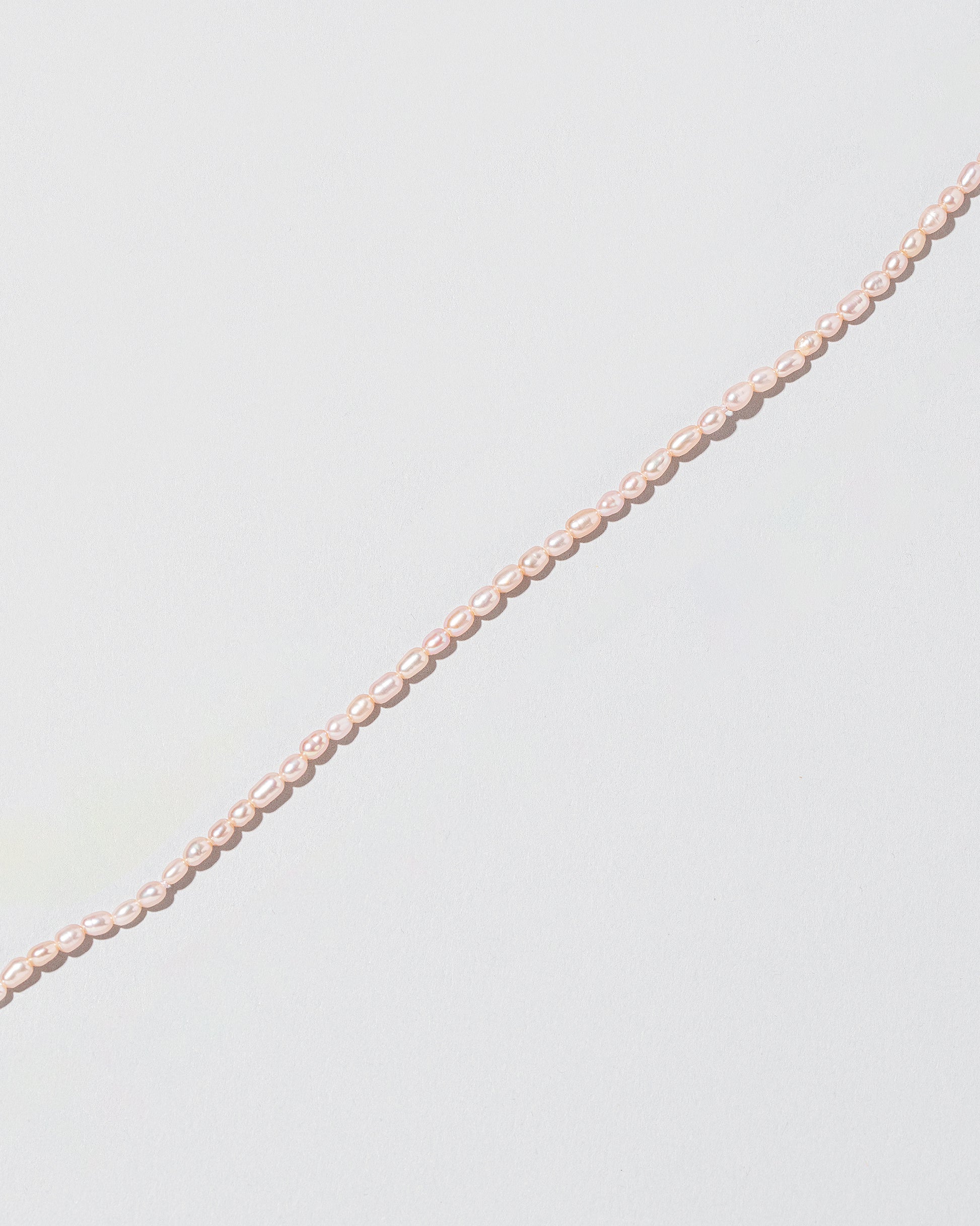 Closeup details of the Pink Peony Oval Seed Pearl Choker Necklace on light color background.