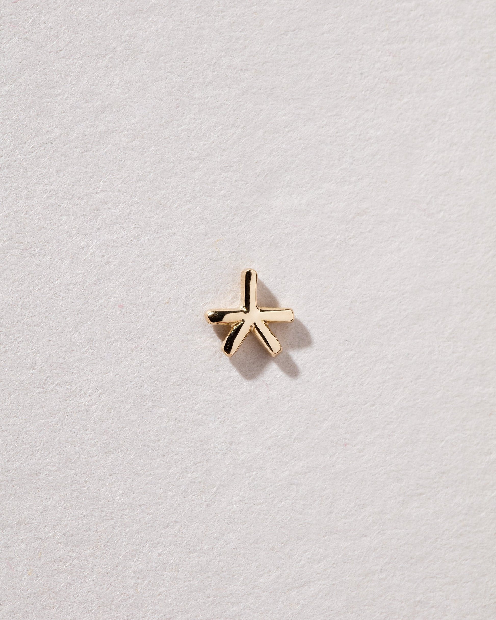 Gold Star Talisman Stud Earring Single on light color background.