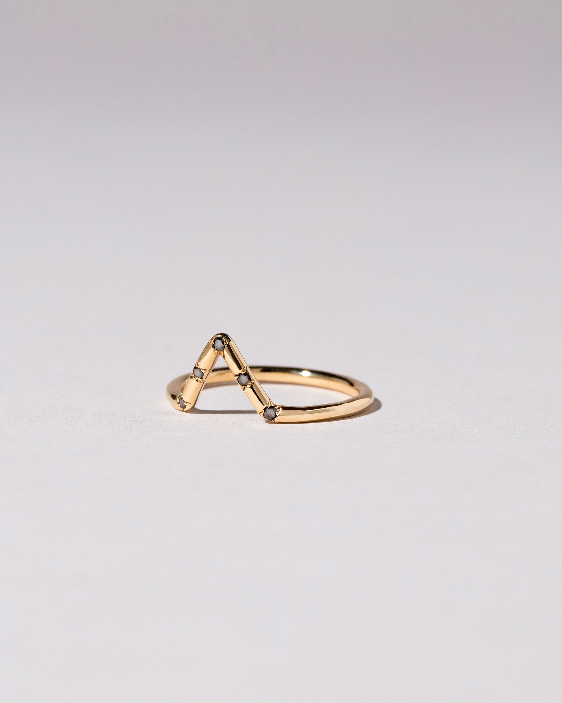 View from the side of the Gold Black Diamond Five Stone Triangle Band on light color background.