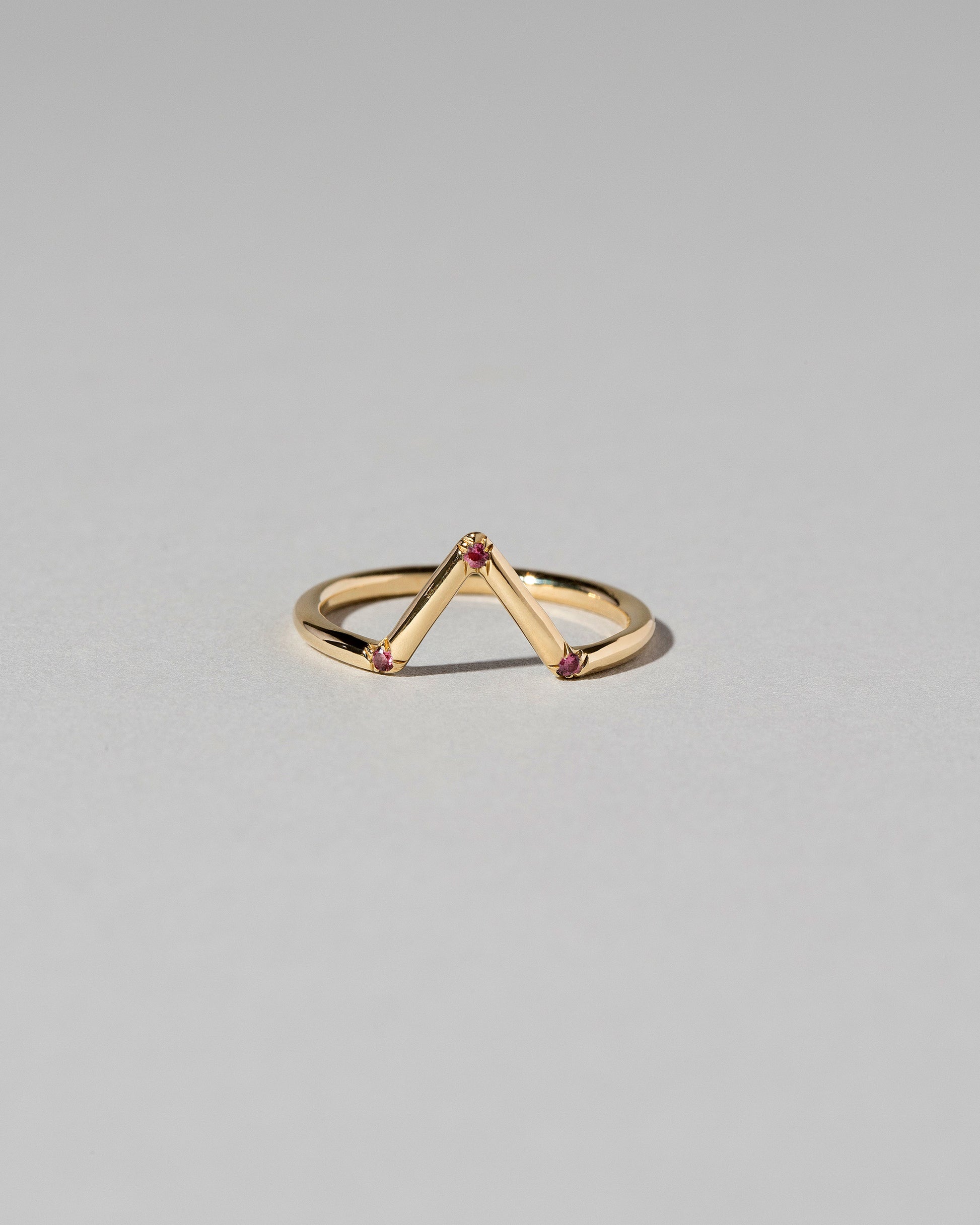 Gold Garnet Three Stone Triangle Band on light color background.