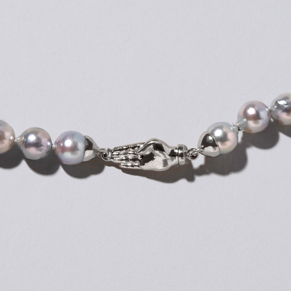 product_details::Closeup detail of the Blue Pearl & White Gold Union Pearl Necklace on light color background.