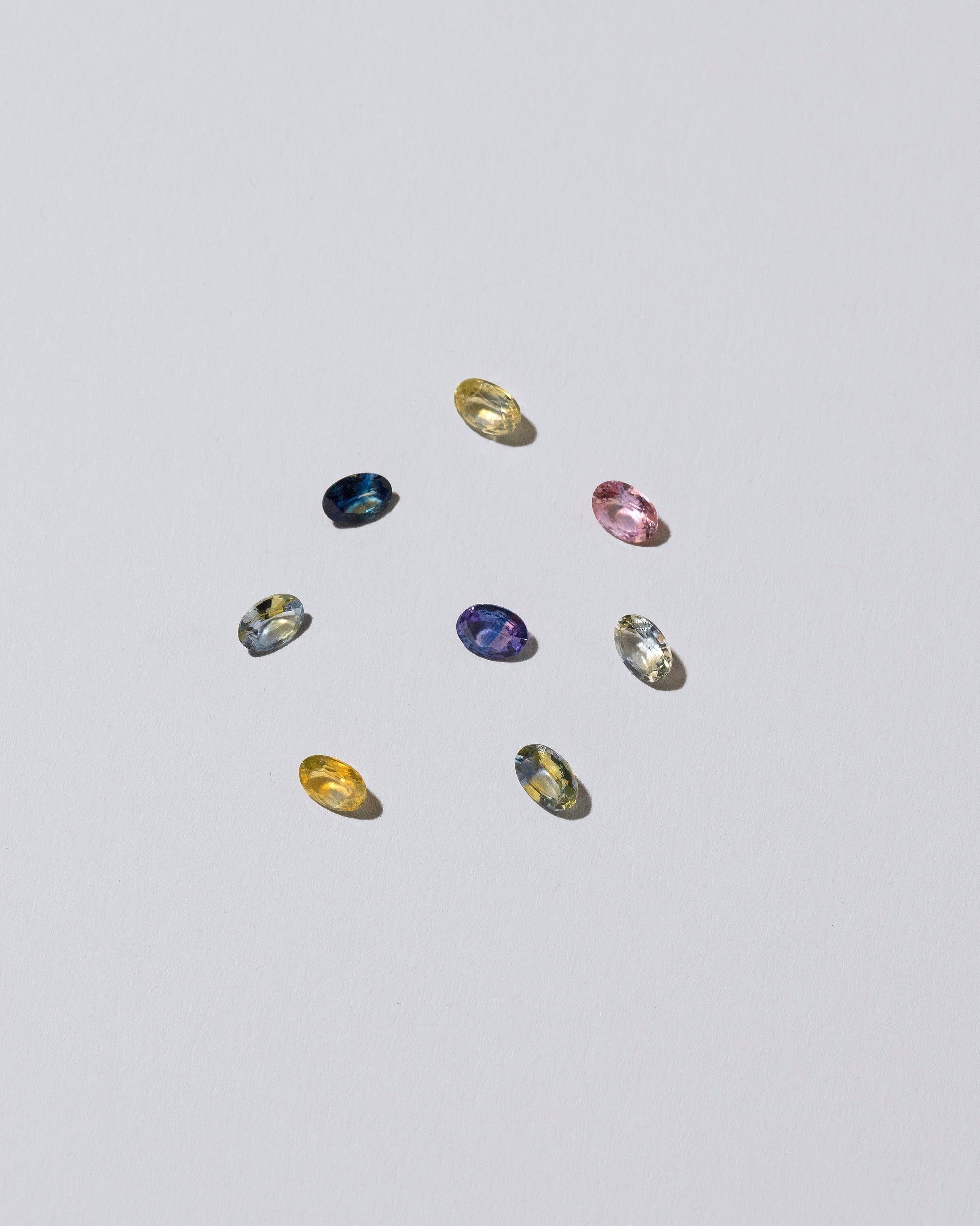Photo of loose, colored gemstones on a light color background.
