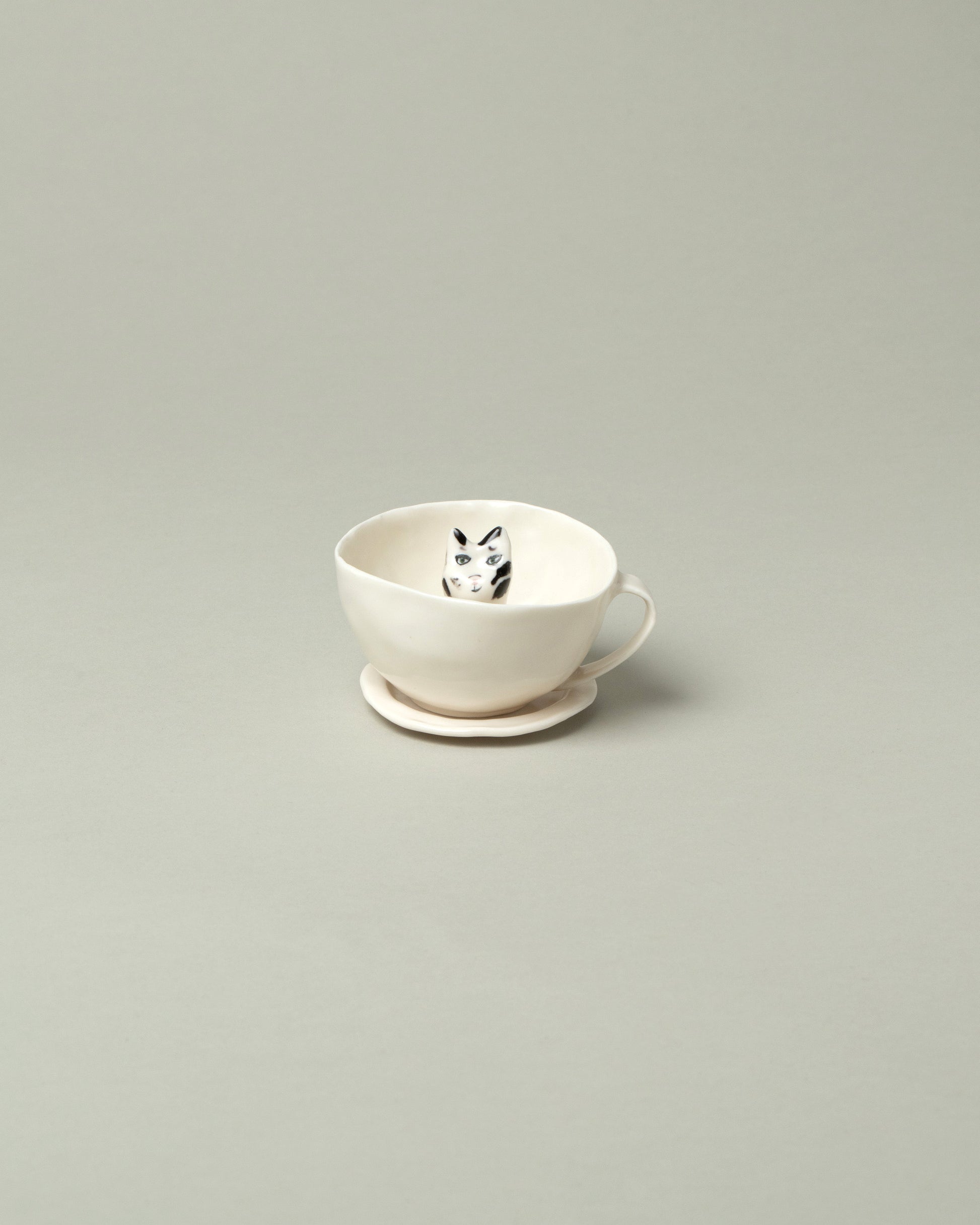Eleonor Boström Black Spots Cat Tea Cup with Saucer on light color background.