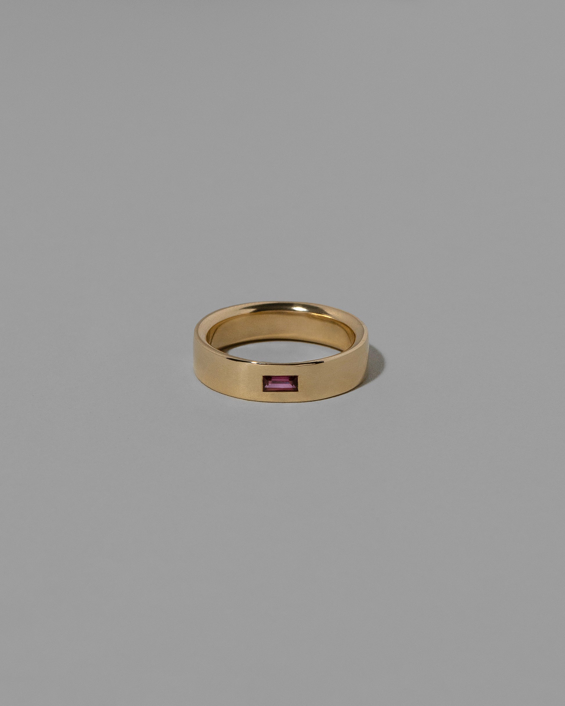 Gold Anthill Red Garnet East West 5mm Baguette-Set Piet Band on light color background.