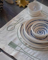 Styled image of the Œuvre Sensibles Green Solo Placemat and Casa Veronica Azul Mini Vida Bowl, Azul Via Bowl and Azul Vida Plate. 