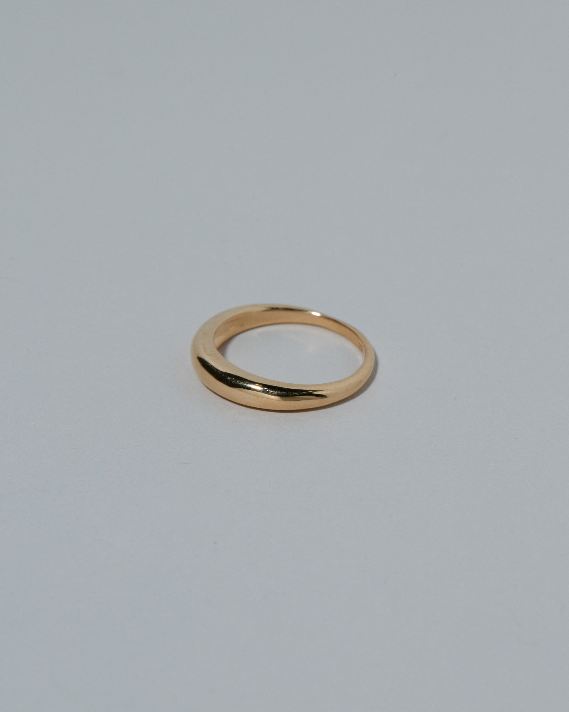 View from the side of the Samples & Imperfects 5mm 18k Yellow Gold Venus Band on light color background.