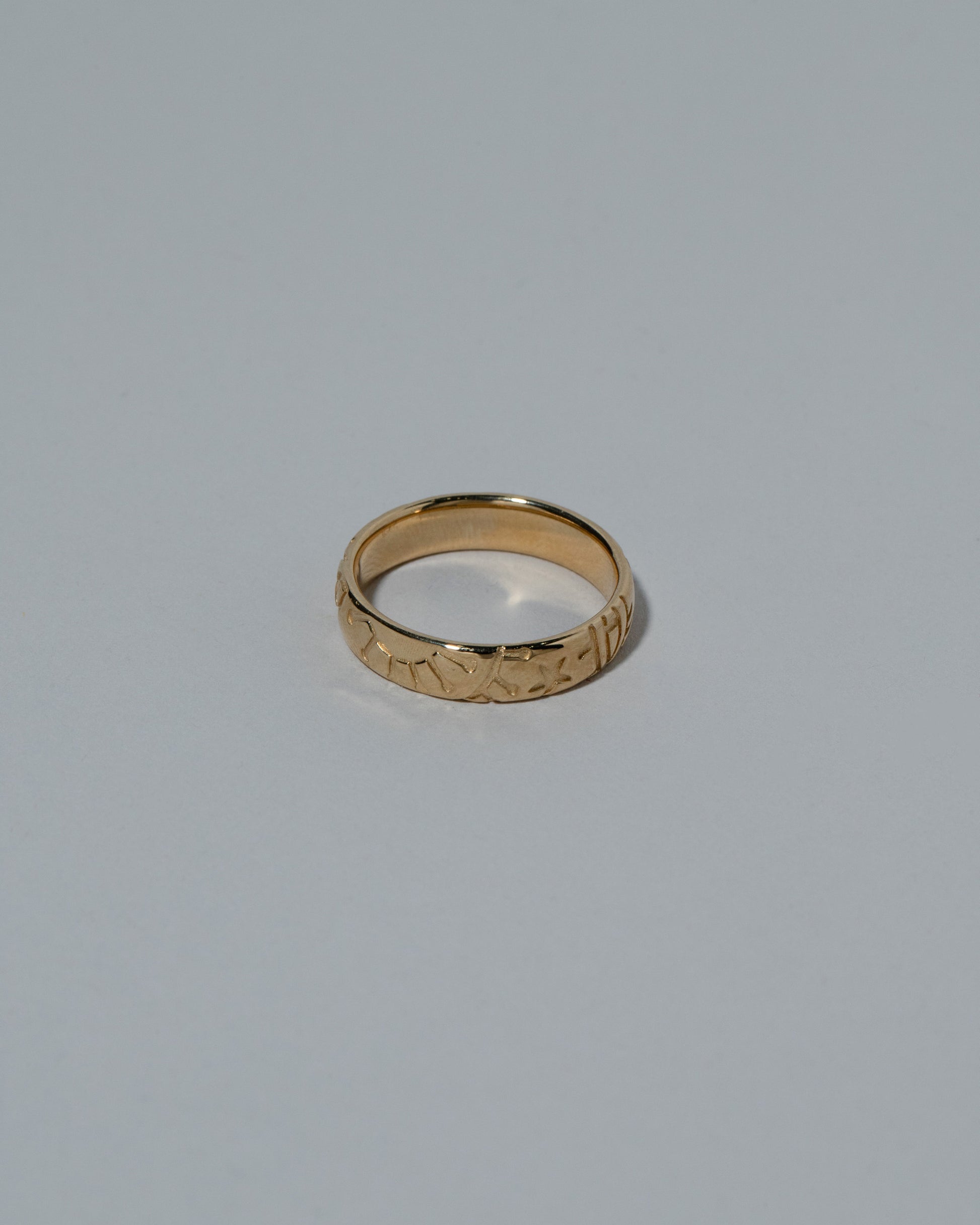 View from the side of the Samples & Imperfects 14k Yellow Gold Tahiti Band on light color background.