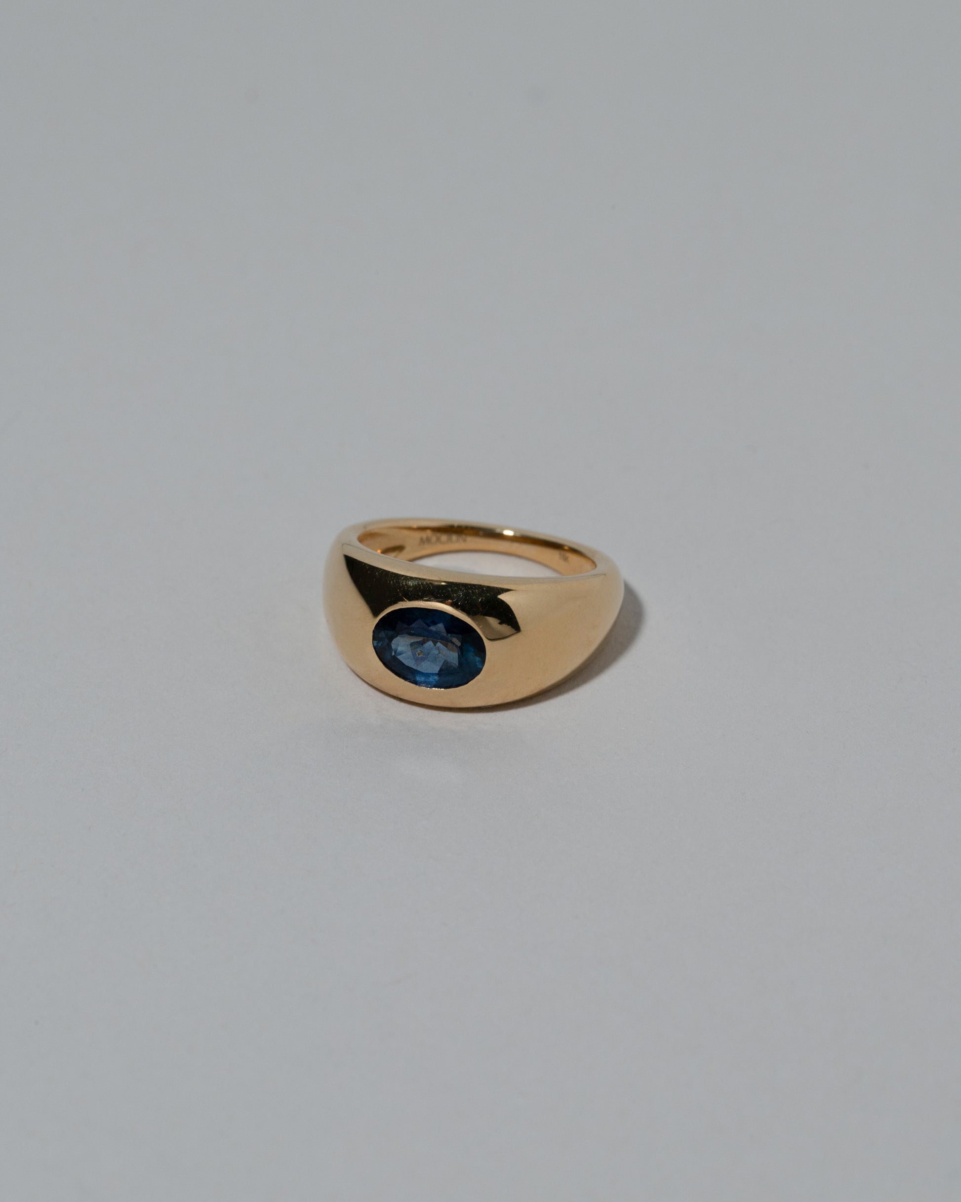 View from the side of the Samples & Imperfects Blue Sapphire Jupiter Ring on light color background.