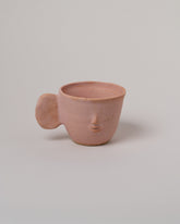 Rami Kim Face Mug With Flat Round Handle on light color background.