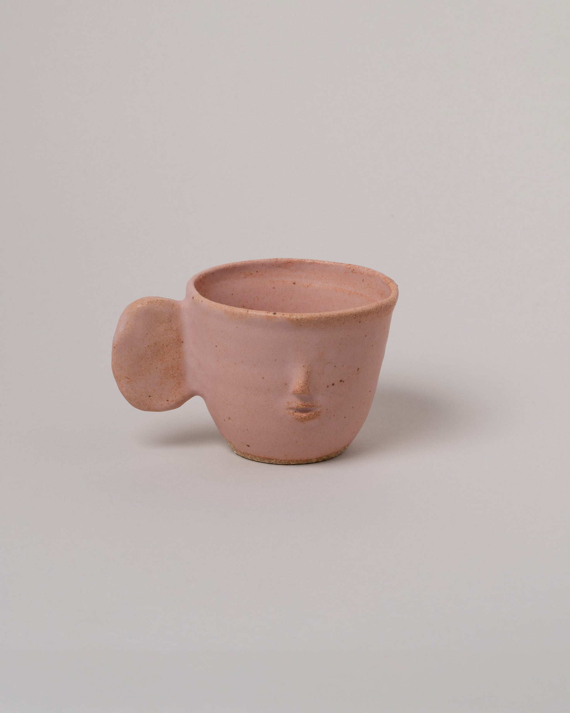 Rami Kim Face Mug With Flat Round Handle on light color background.