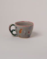 Rami Kim Orange Dream Face Mug With Double Loop Handle on light color background.